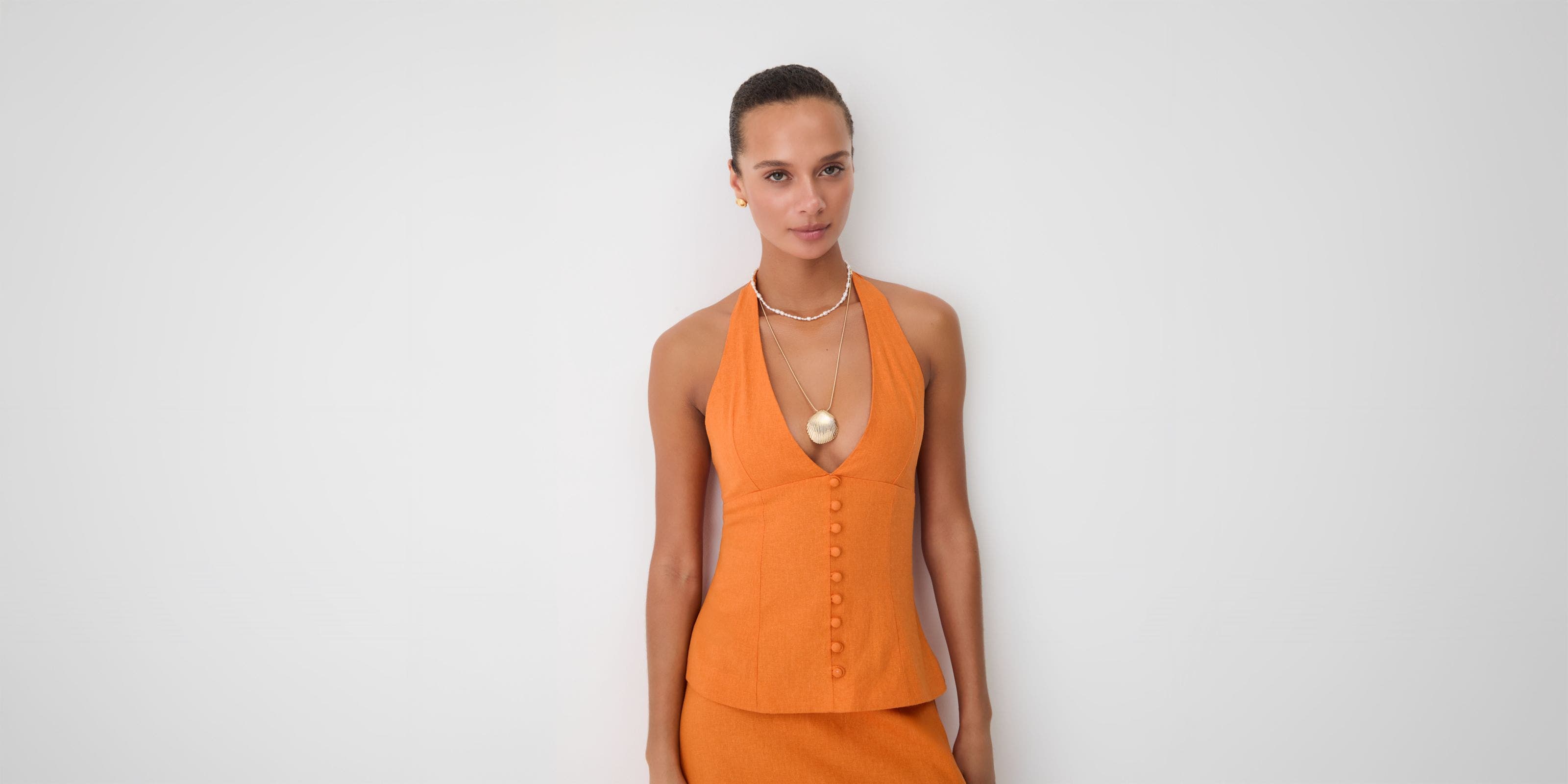 A woman wearing an orange halter top. 