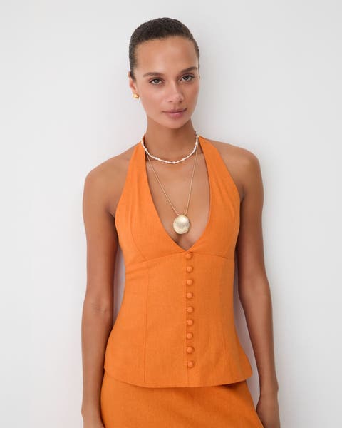 A woman wearing an orange halter top.
