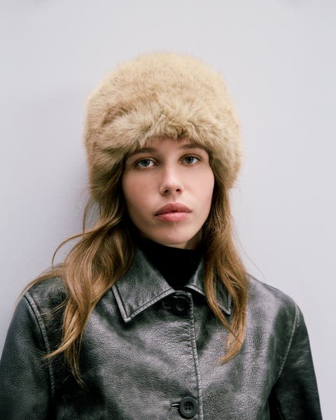 Woman wearing a faux-fur hat and black leather jacket.