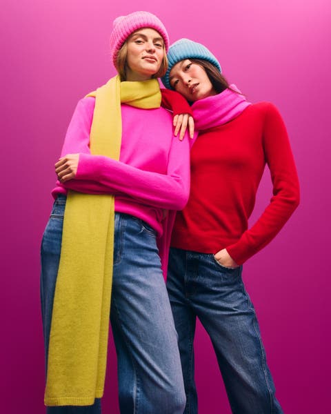 Two women in bright sweaters, scarves and hats.