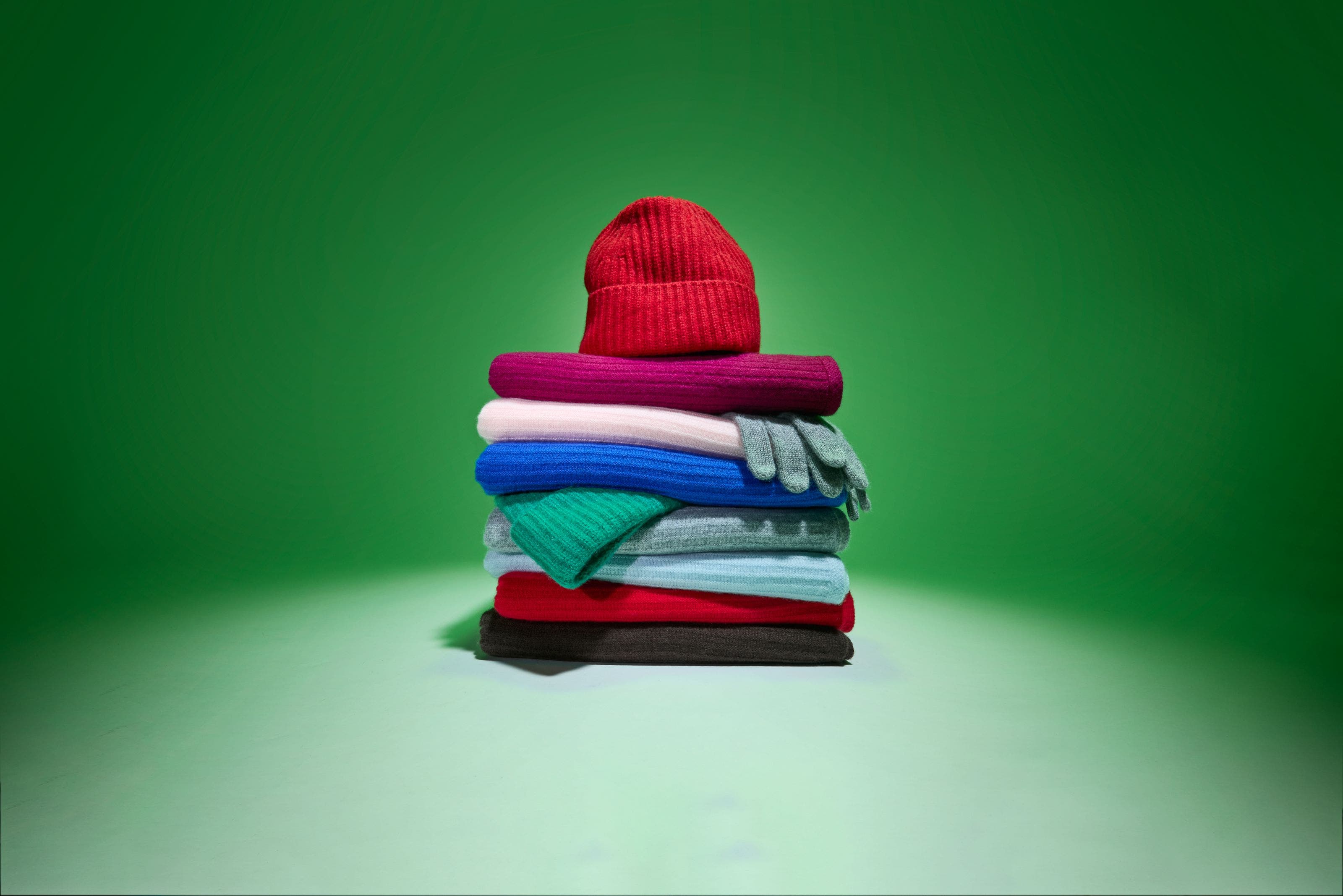 A stack of cashmere scarves, gloves and beanies. 