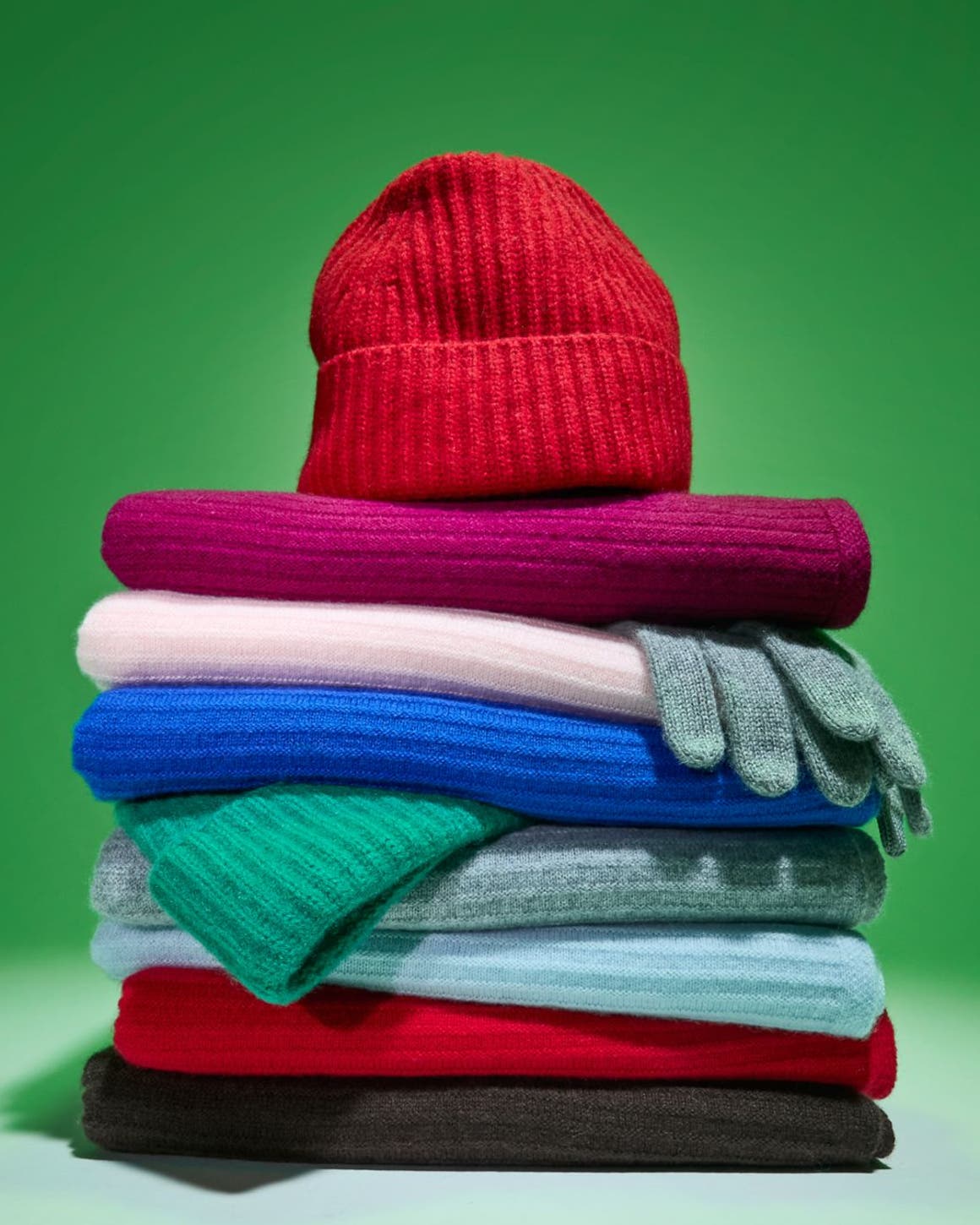A stack of cashmere scarves, gloves and beanies.