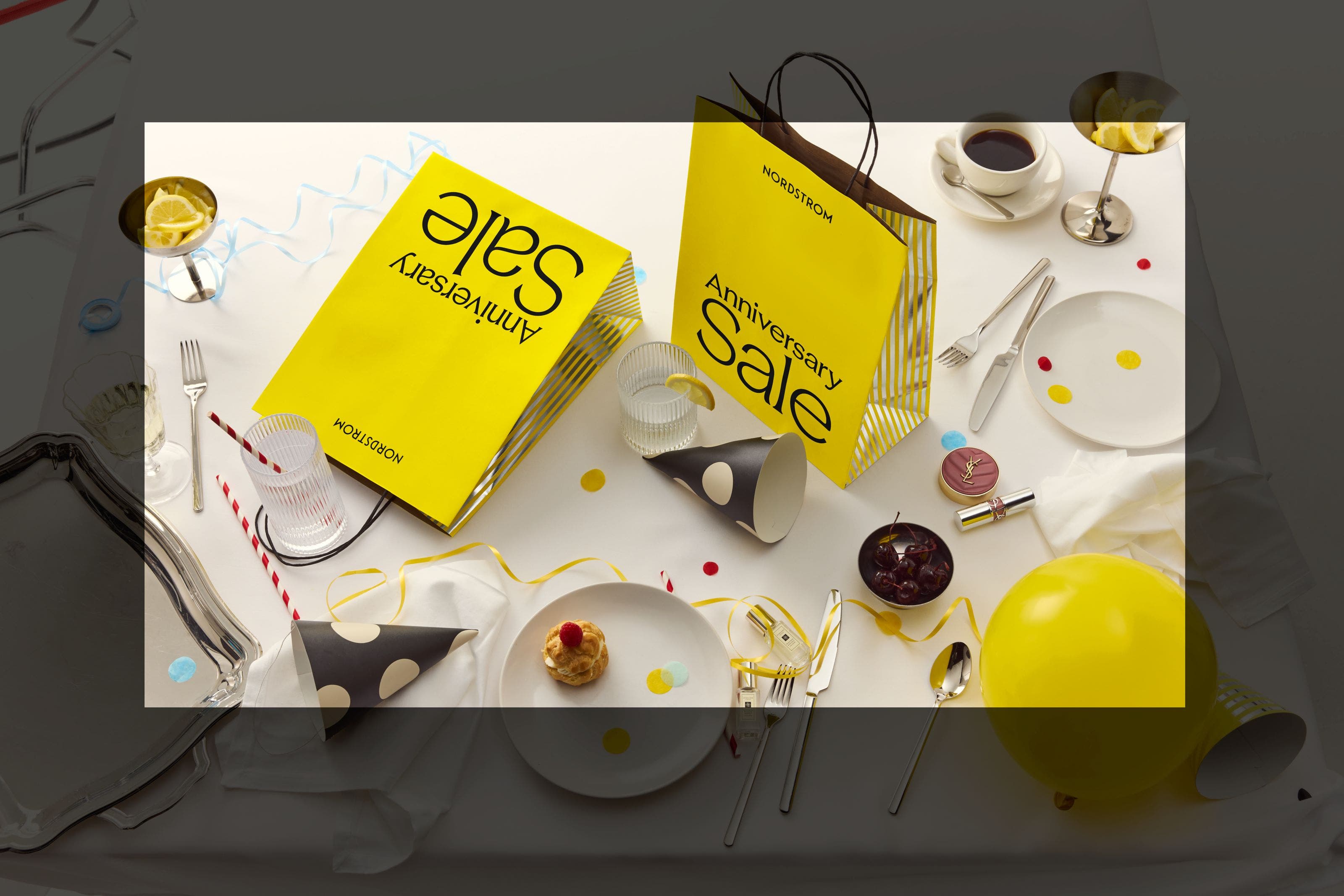 Scattered items with a yellow anniversary sale bag.