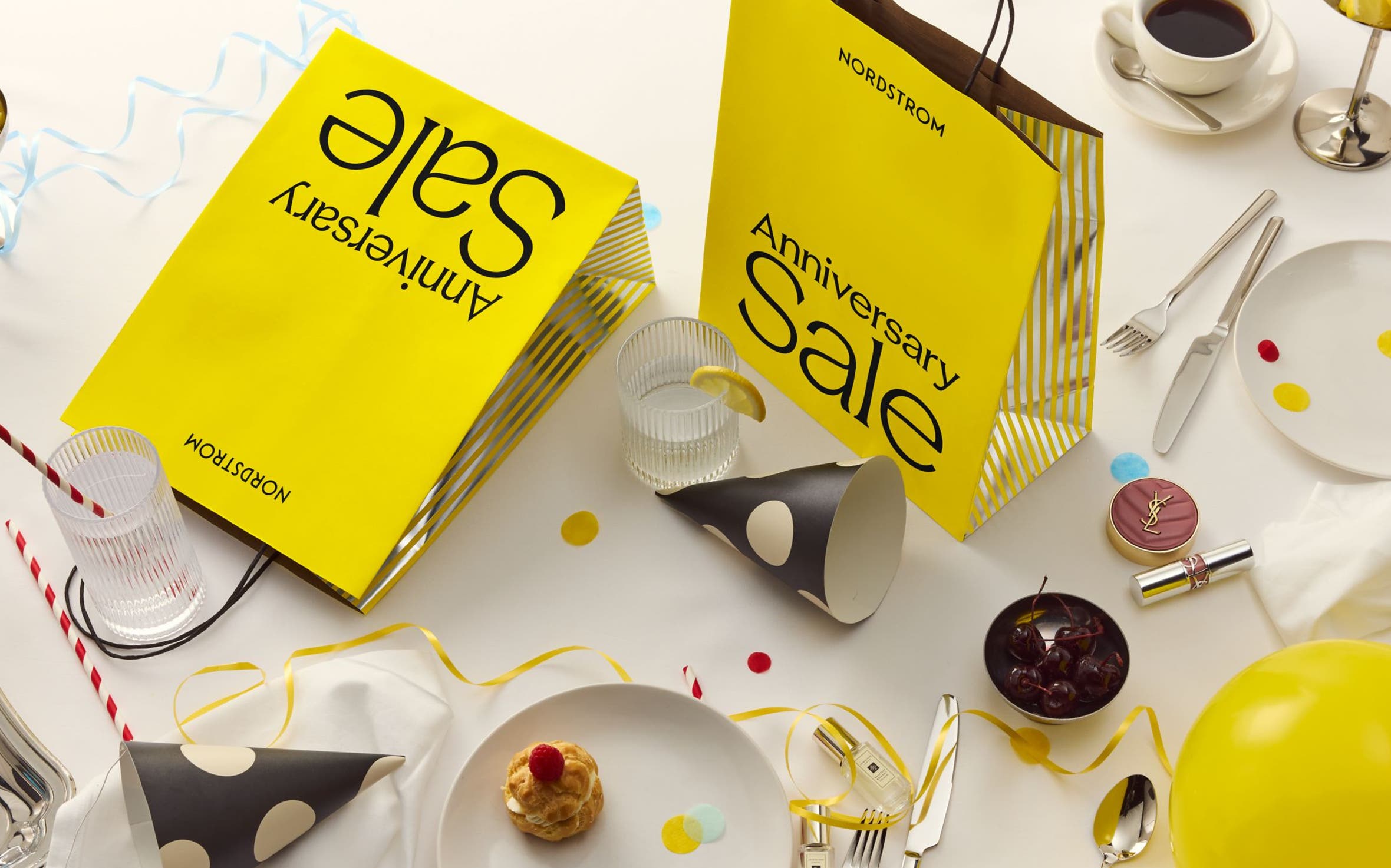 Scattered items with a yellow anniversary sale bag.