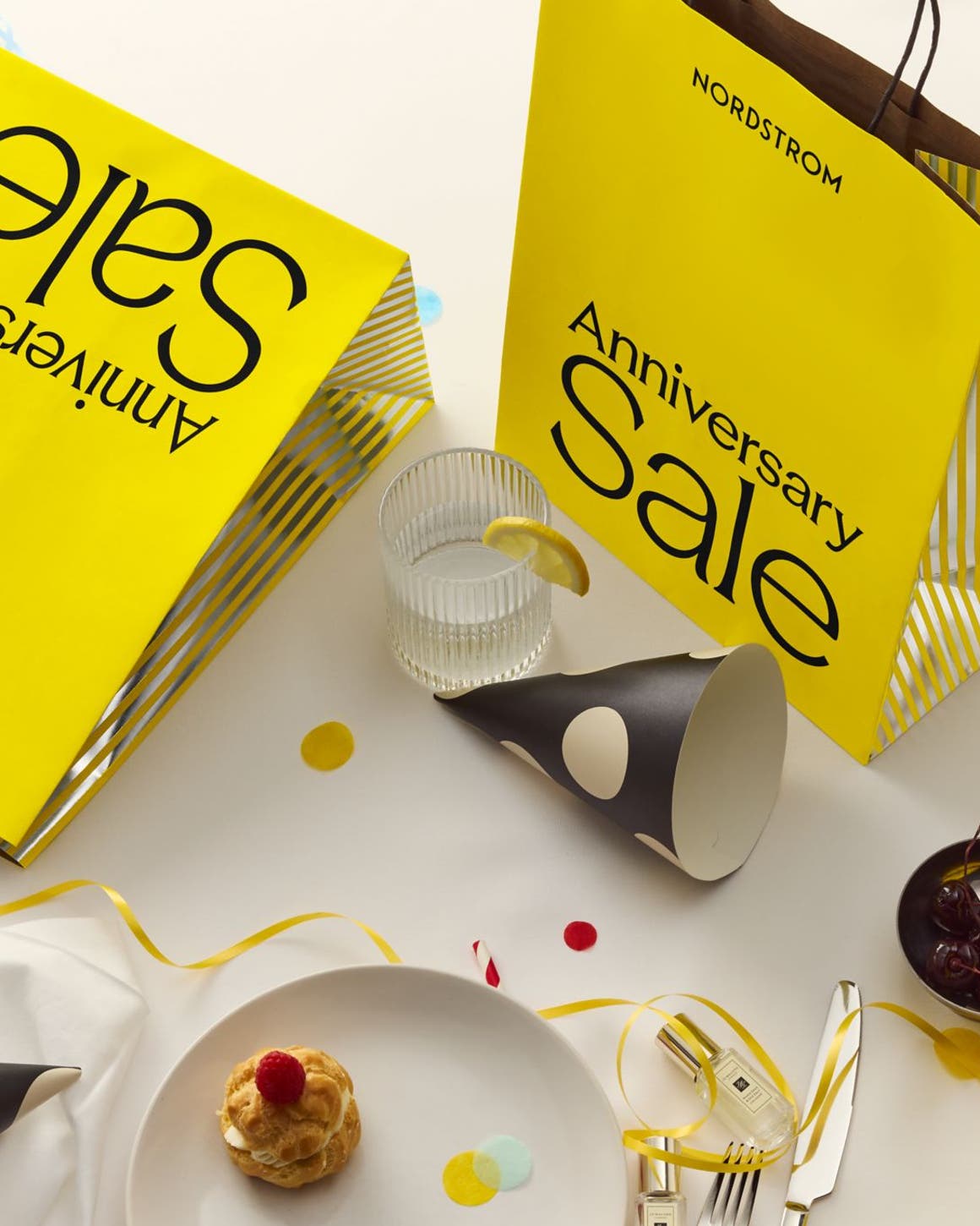 Scattered items with a yellow anniversary sale bag.