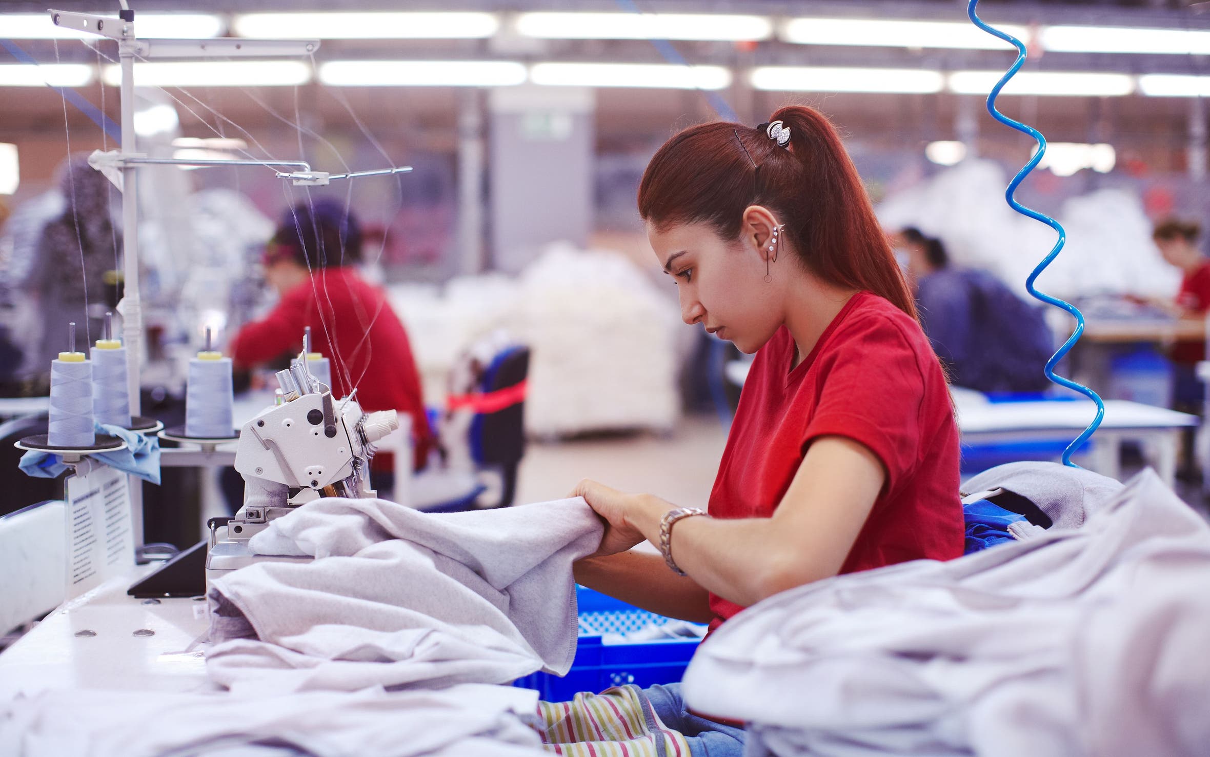 Woman working on a garment on a sewing machine.