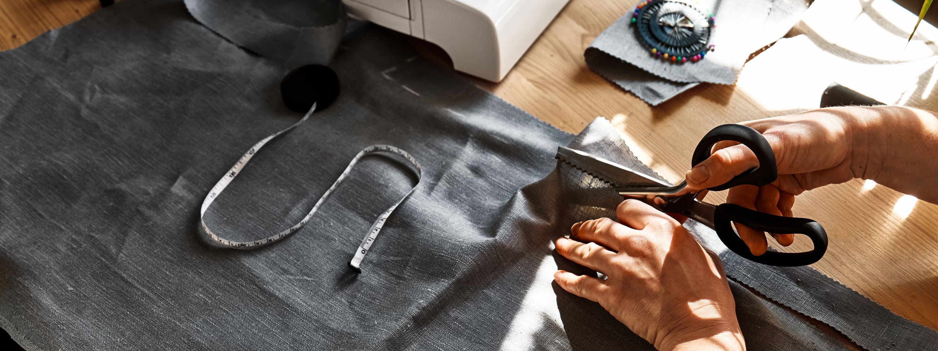 Hands using scissors to cut fabric.