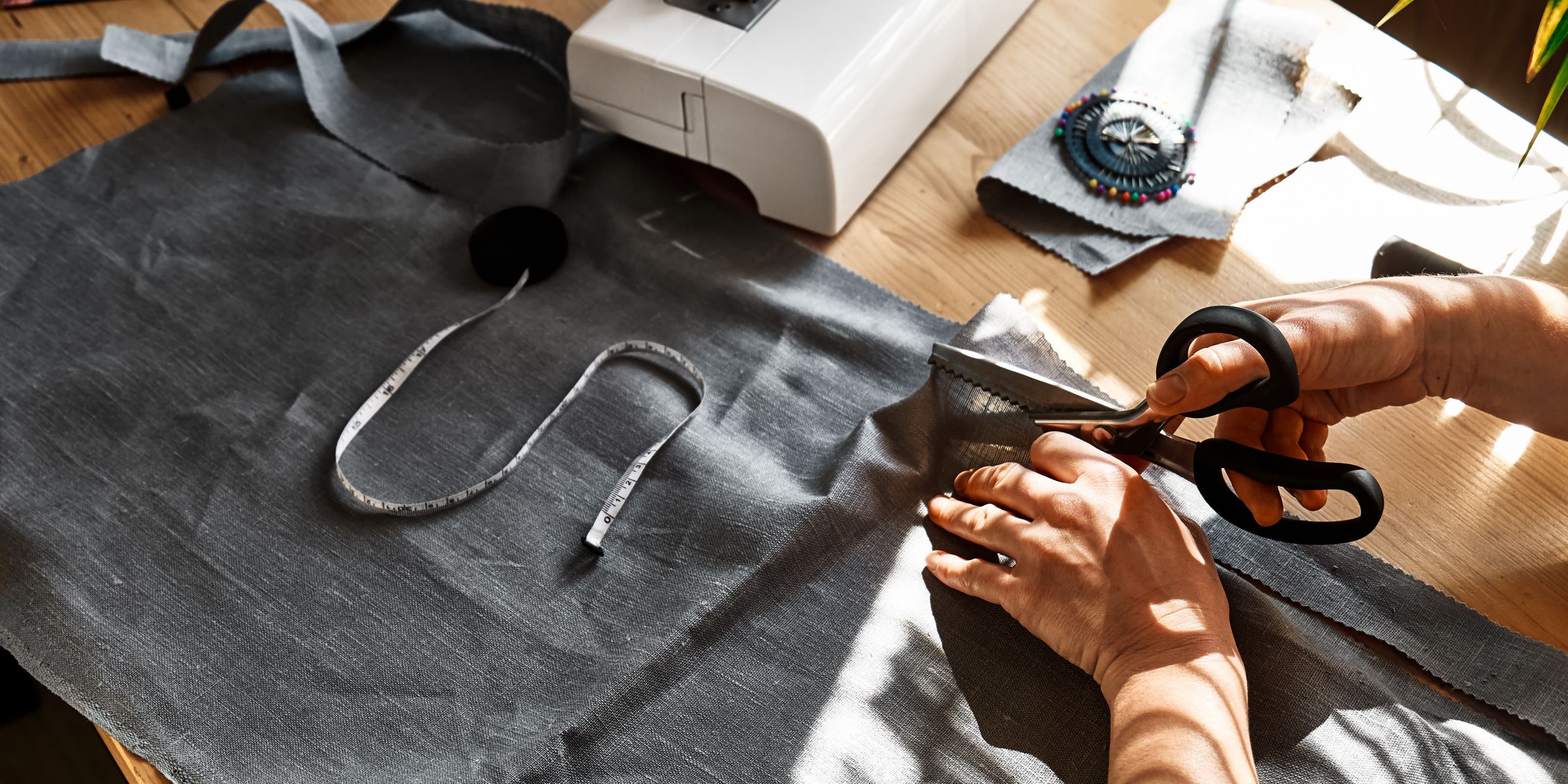 Hands using scissors to cut fabric.