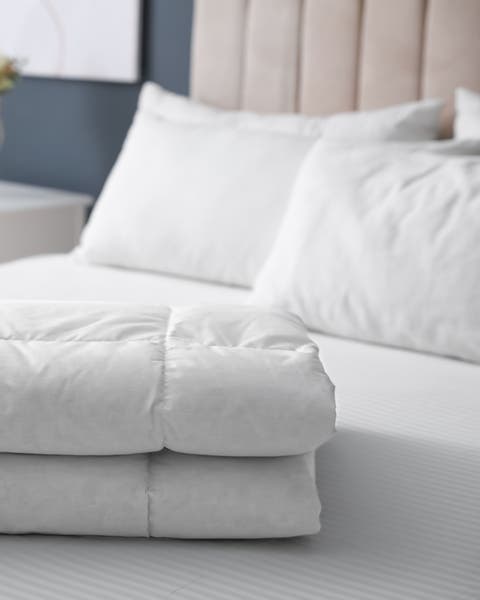 A white down comforter on a bed.