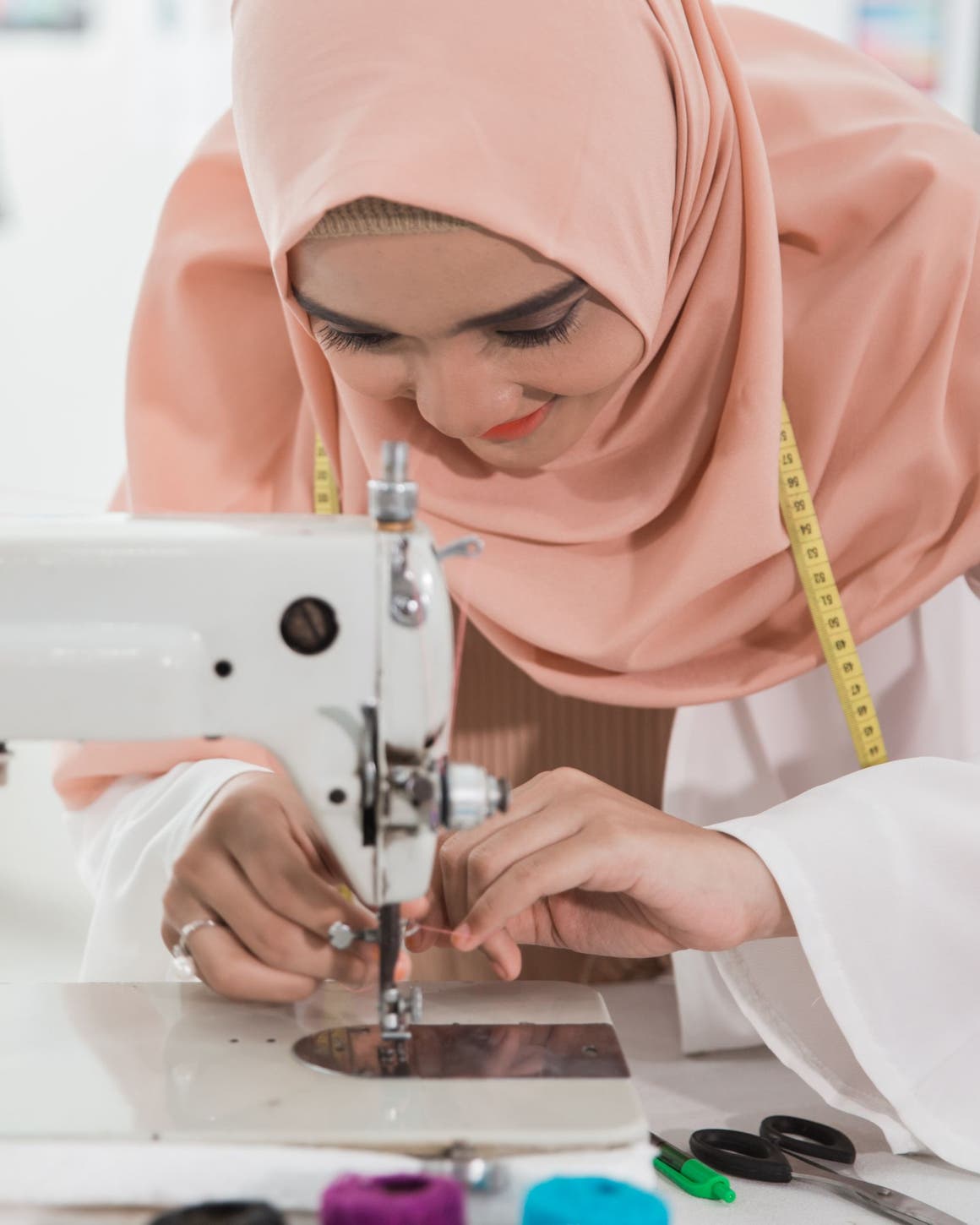 A woman threading a sewing machine.