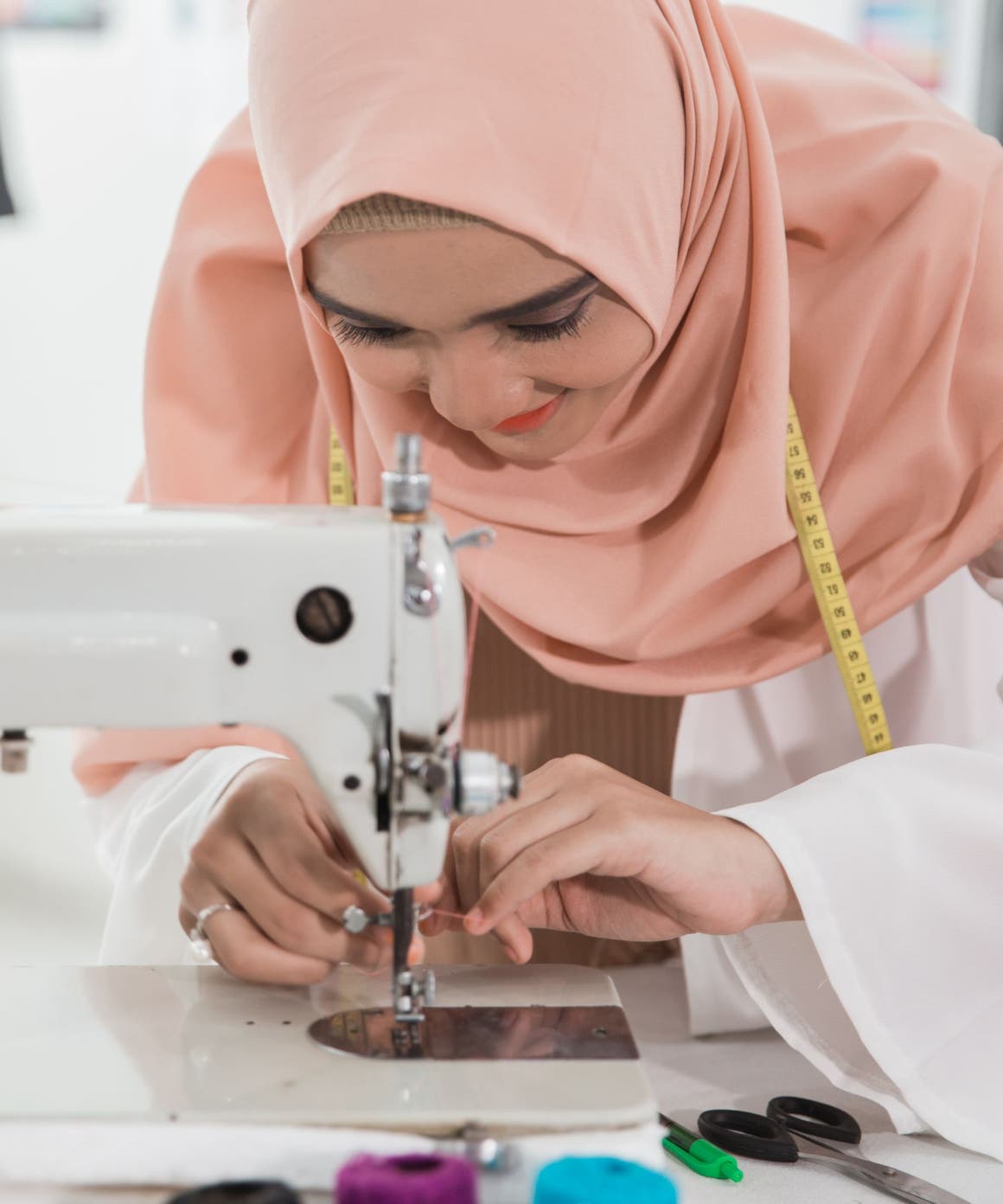 A woman threading a sewing machine.