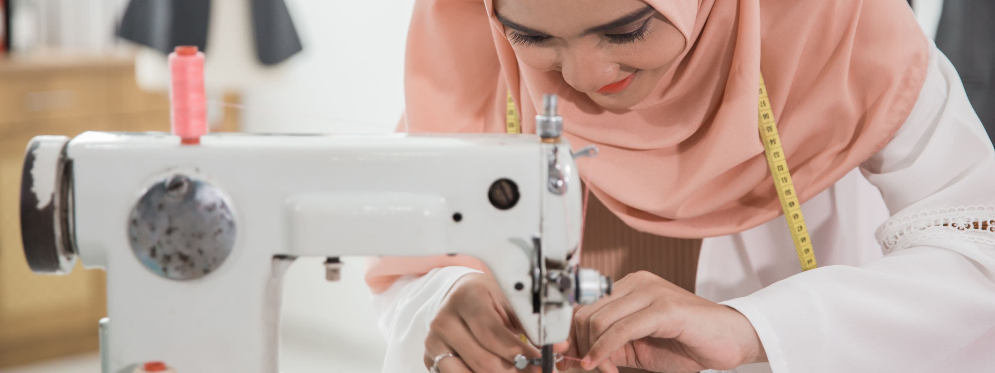 A woman threading a sewing machine.