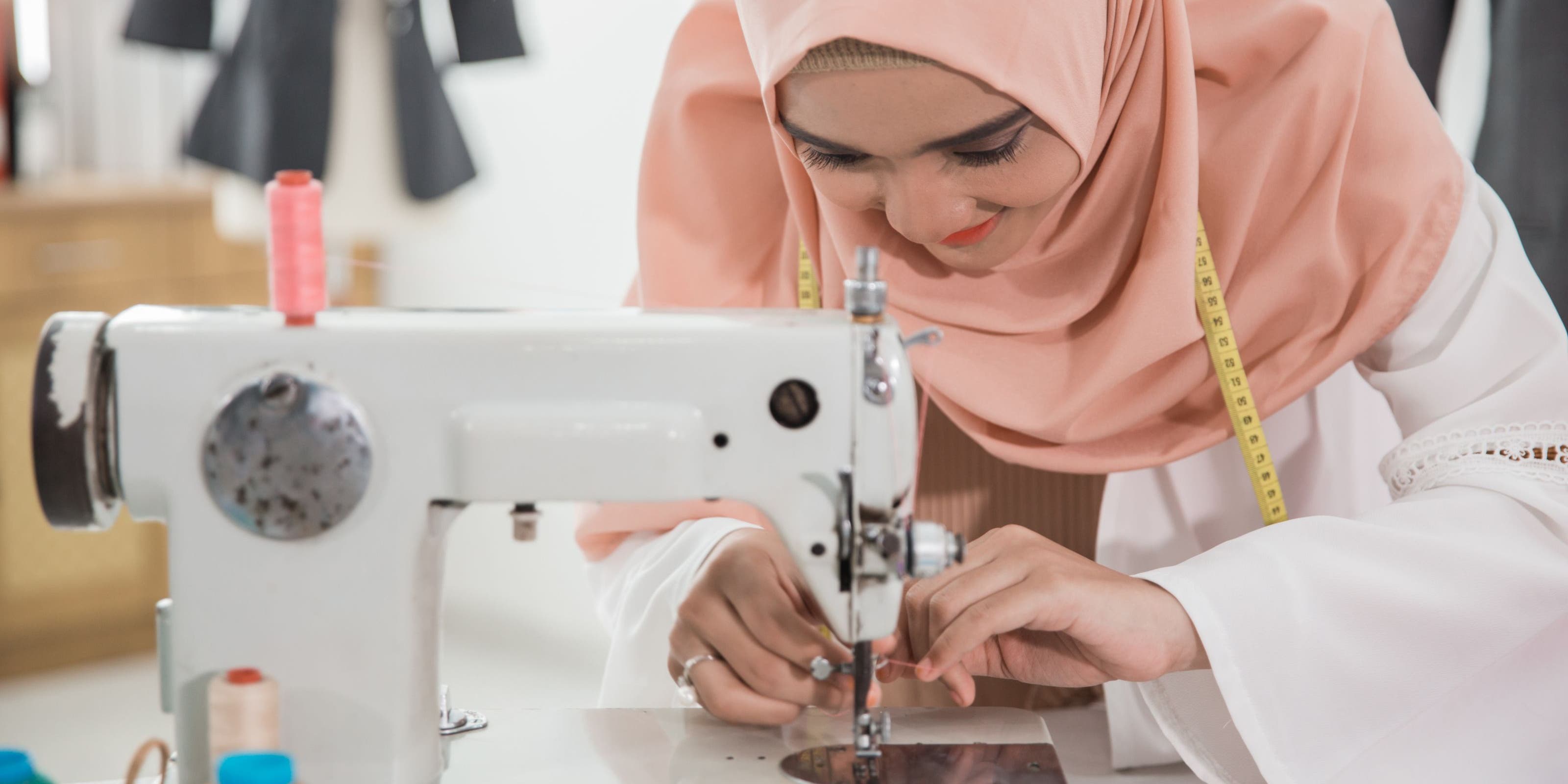 A woman threading a sewing machine.