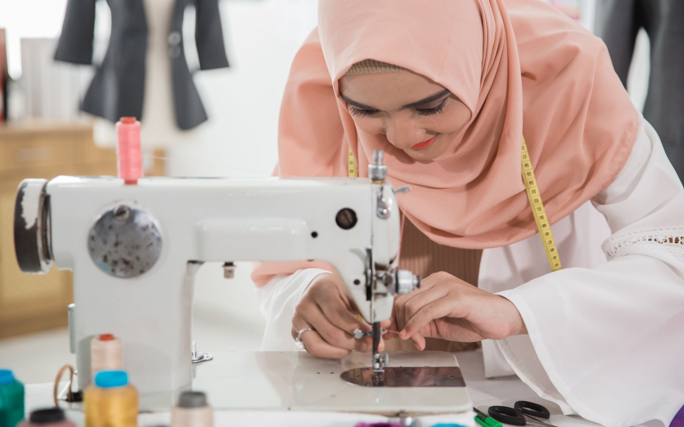 A woman threading a sewing machine.