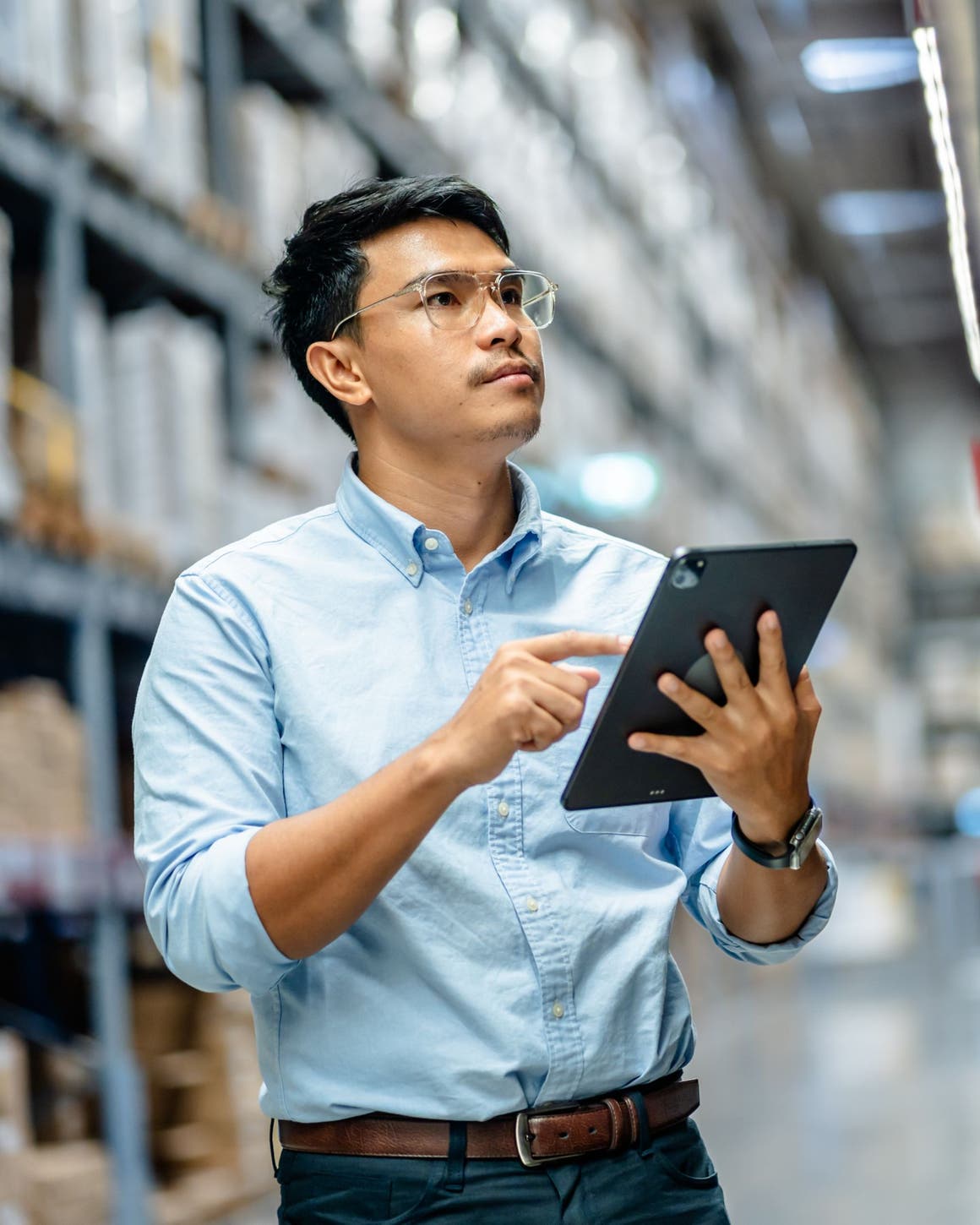 A man in a warehouse holding a tablet.
