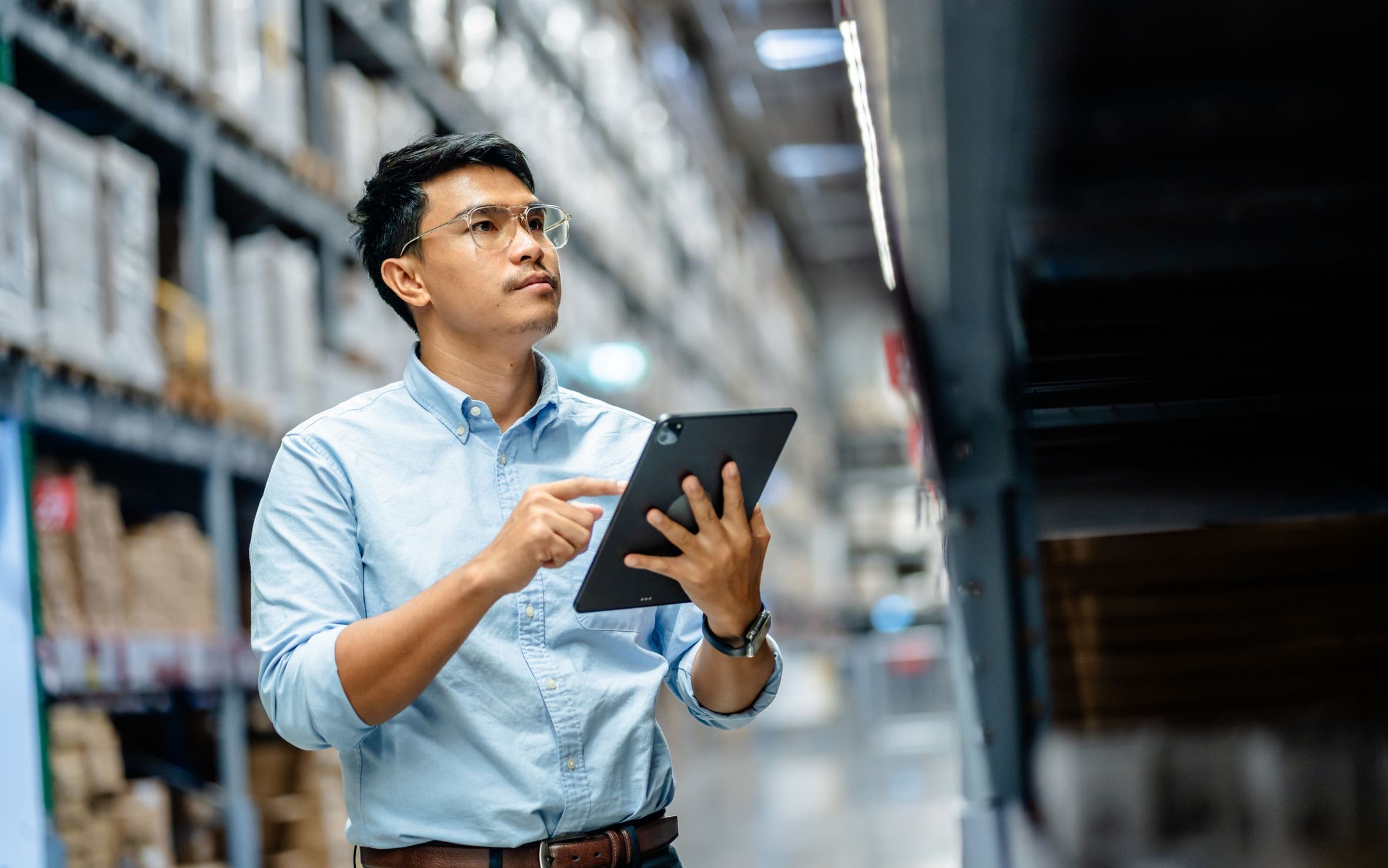 A man in a warehouse holding a tablet.