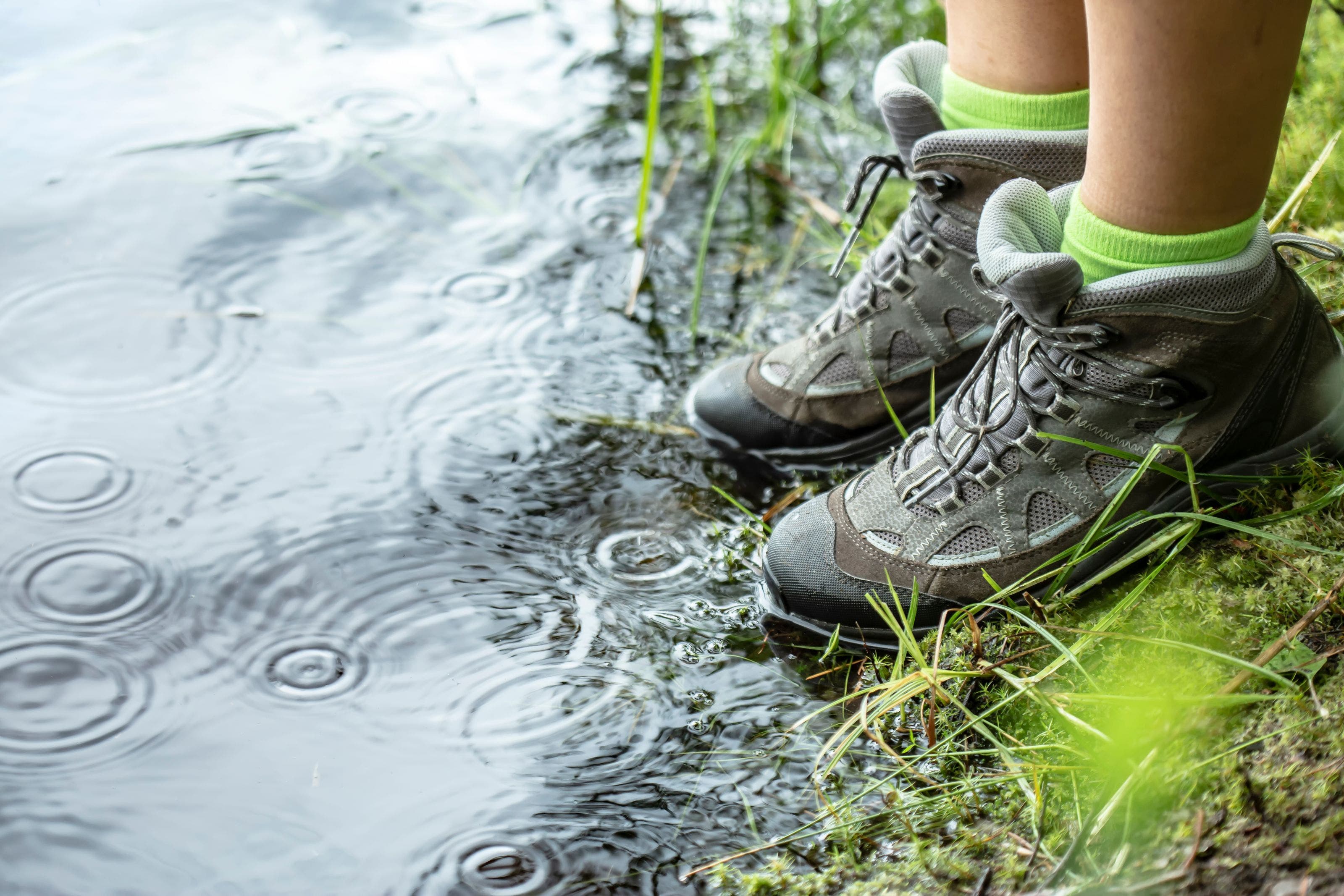 A person in hiking shoes standing at the water's edge.