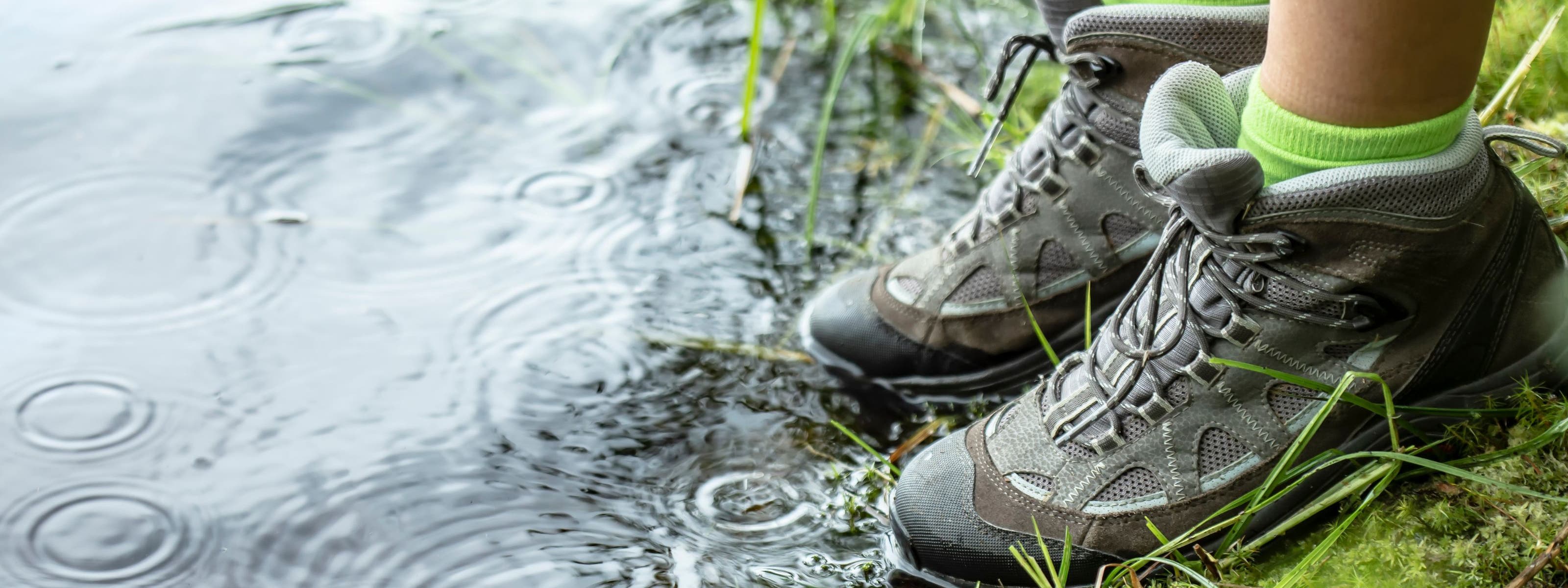 A person in hiking shoes standing at the water's edge.