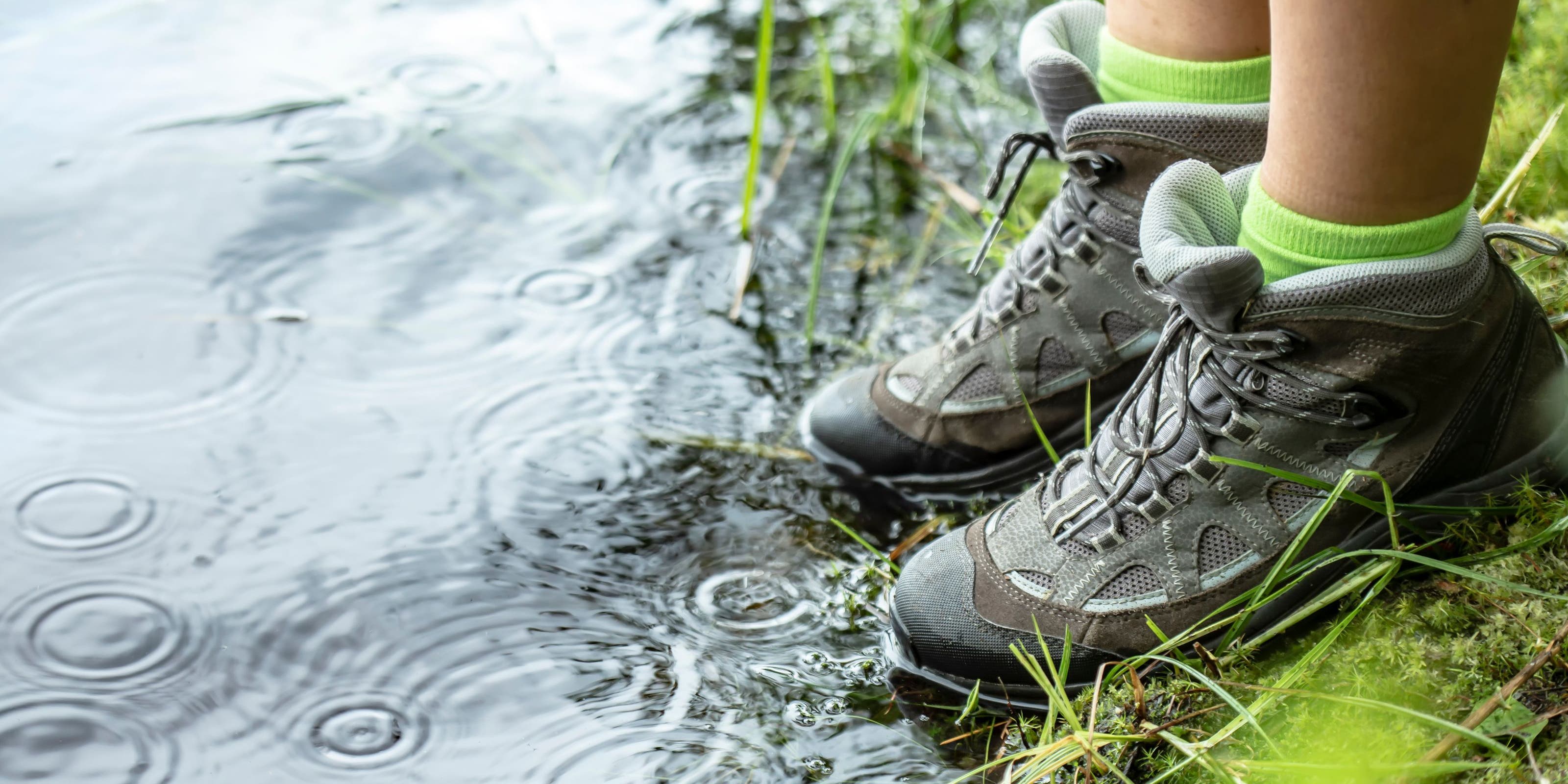 A person in hiking shoes standing at the water's edge.
