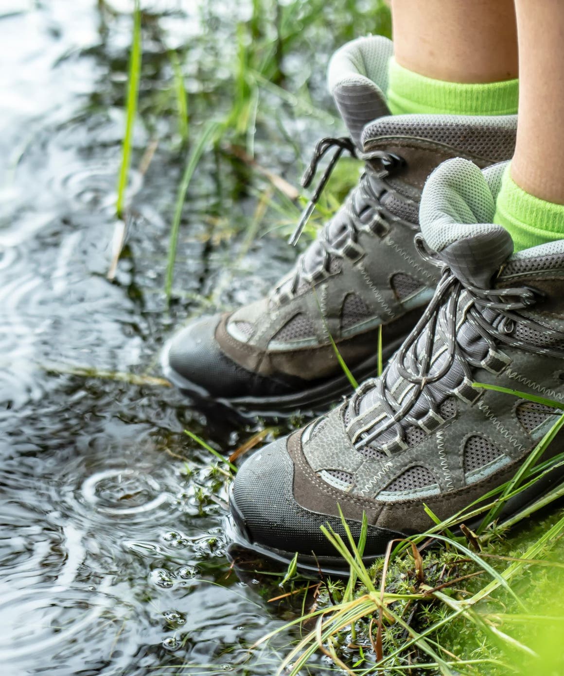A person in hiking shoes standing at the water's edge.