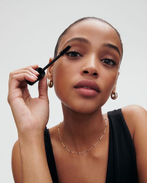 A woman applying mascara.