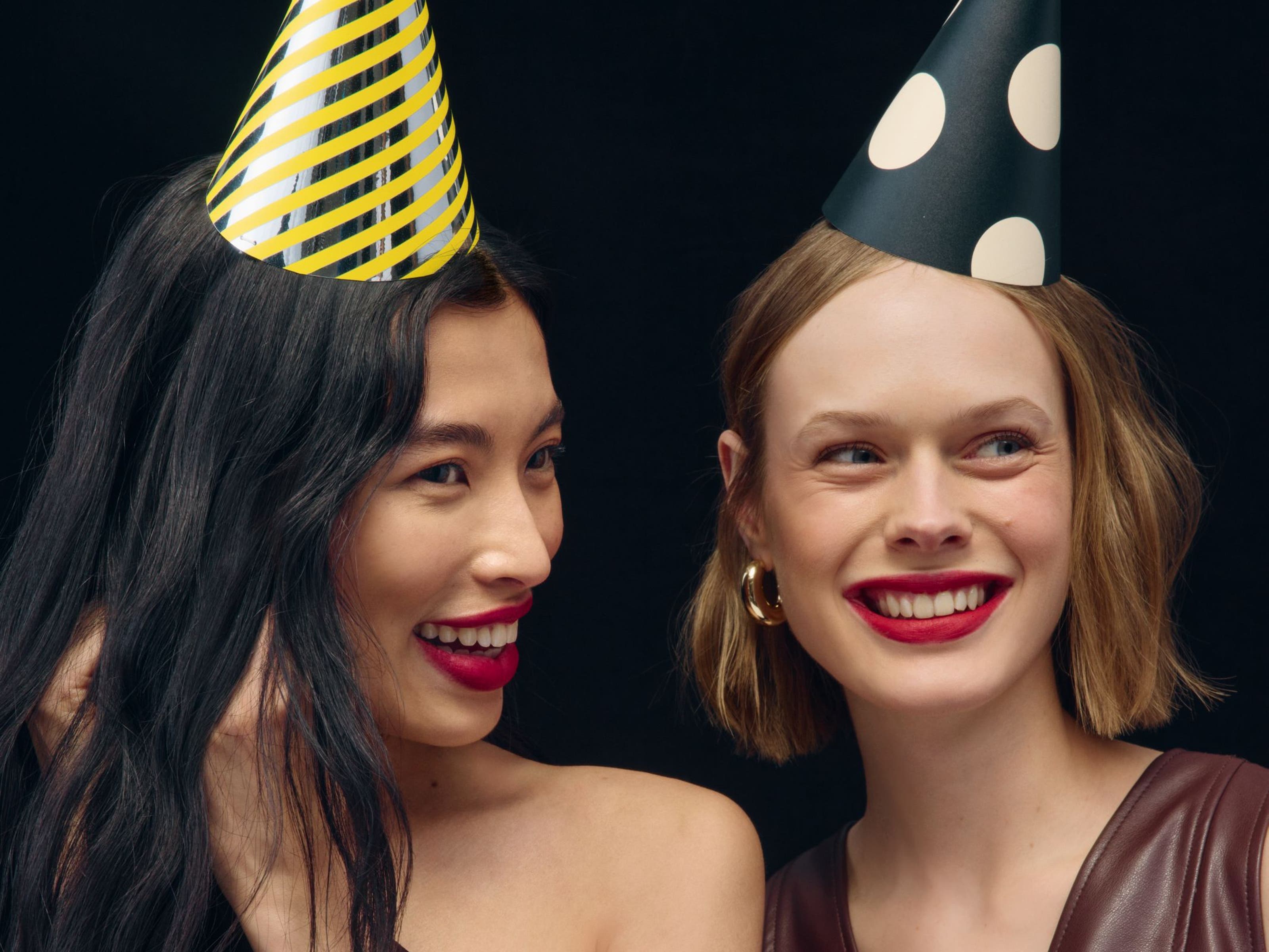 Two women wearing party hats. 