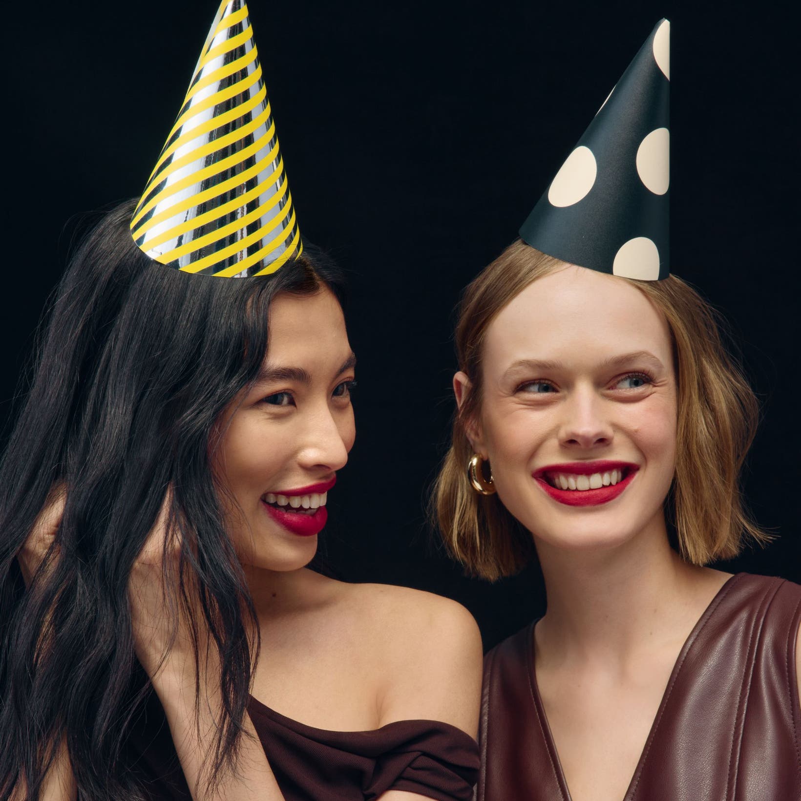 Two women wearing party hats. 
