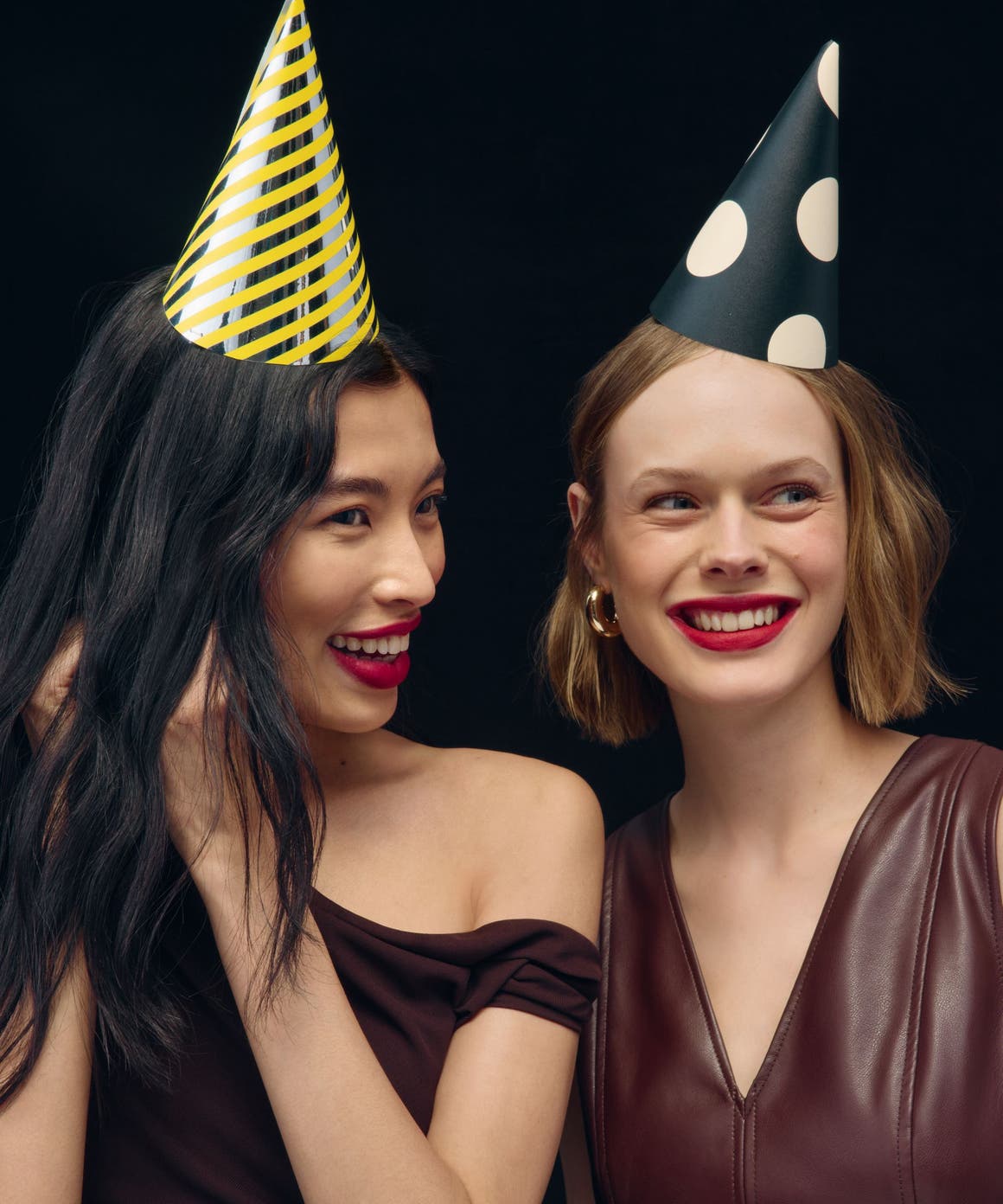 Two women wearing party hats. 
