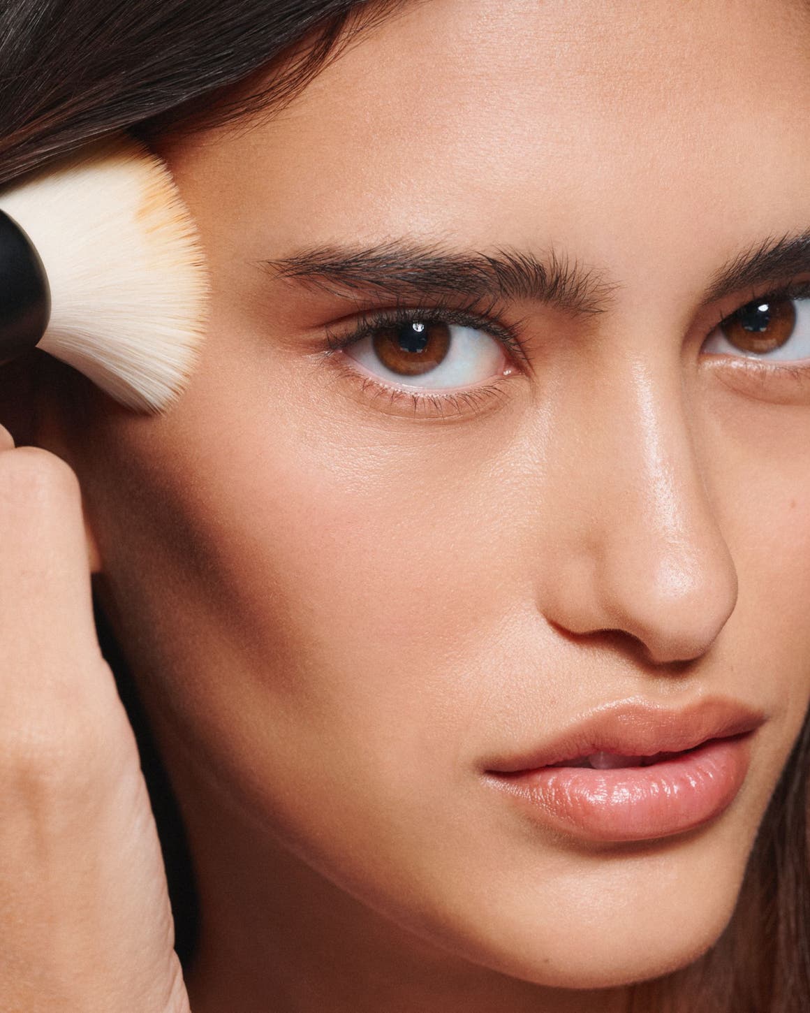 A woman apply makeup with a brush. 