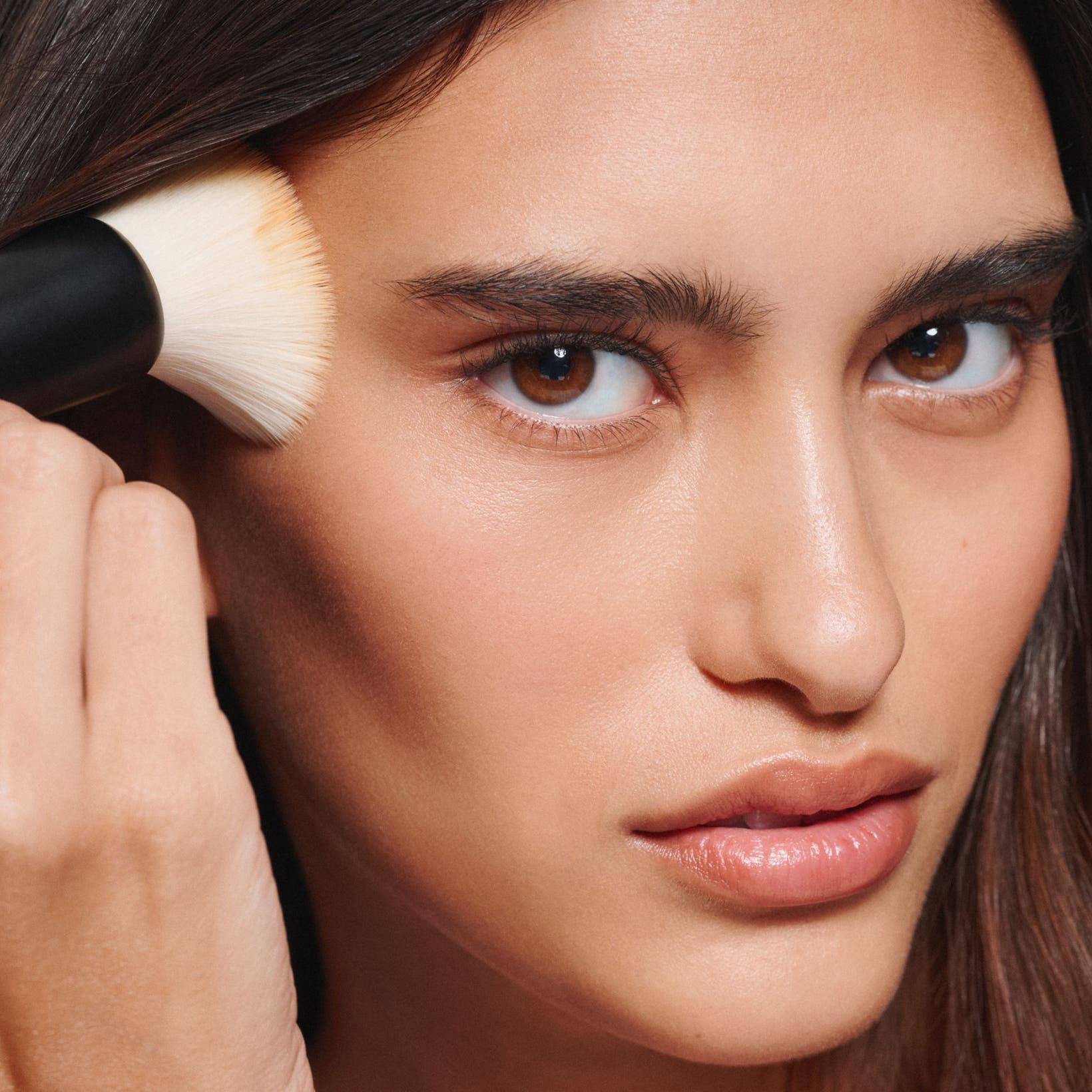 A woman apply makeup with a brush. 