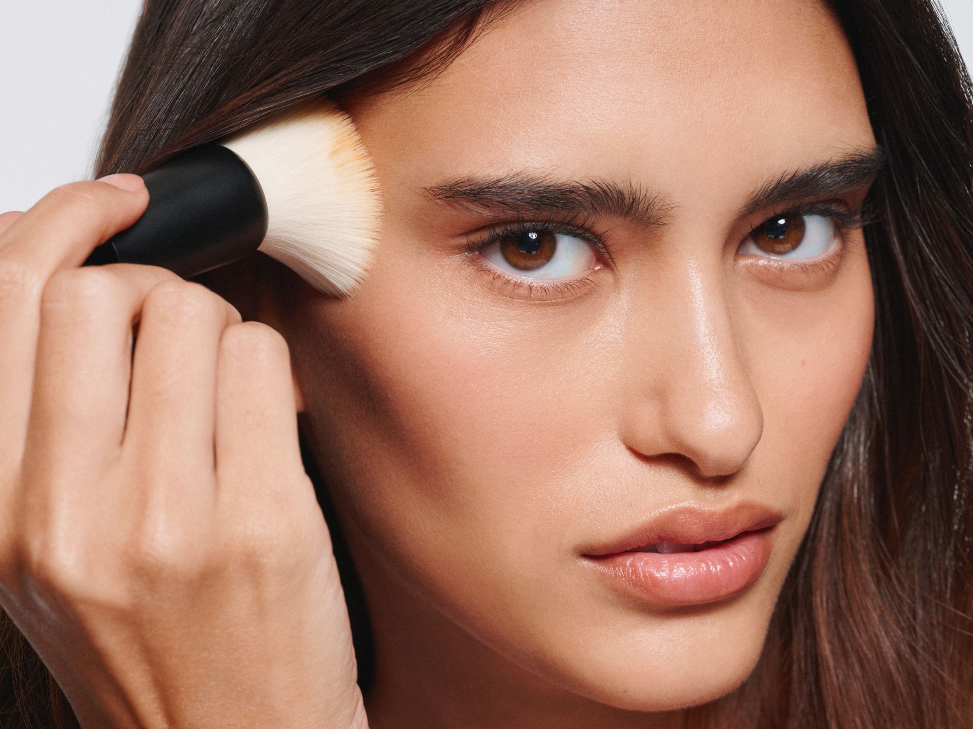 A woman apply makeup with a brush. 