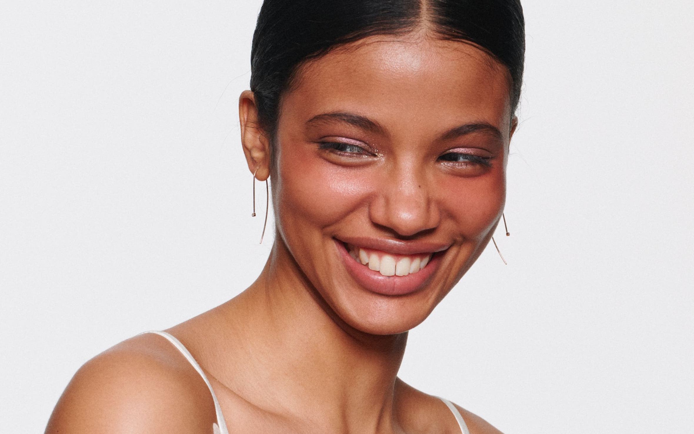 A smiling woman with sparkly eyeshadow.