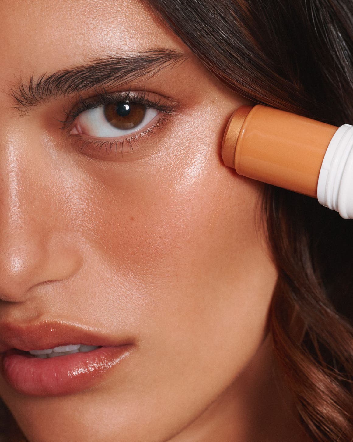 A woman applying a golden highlighter.