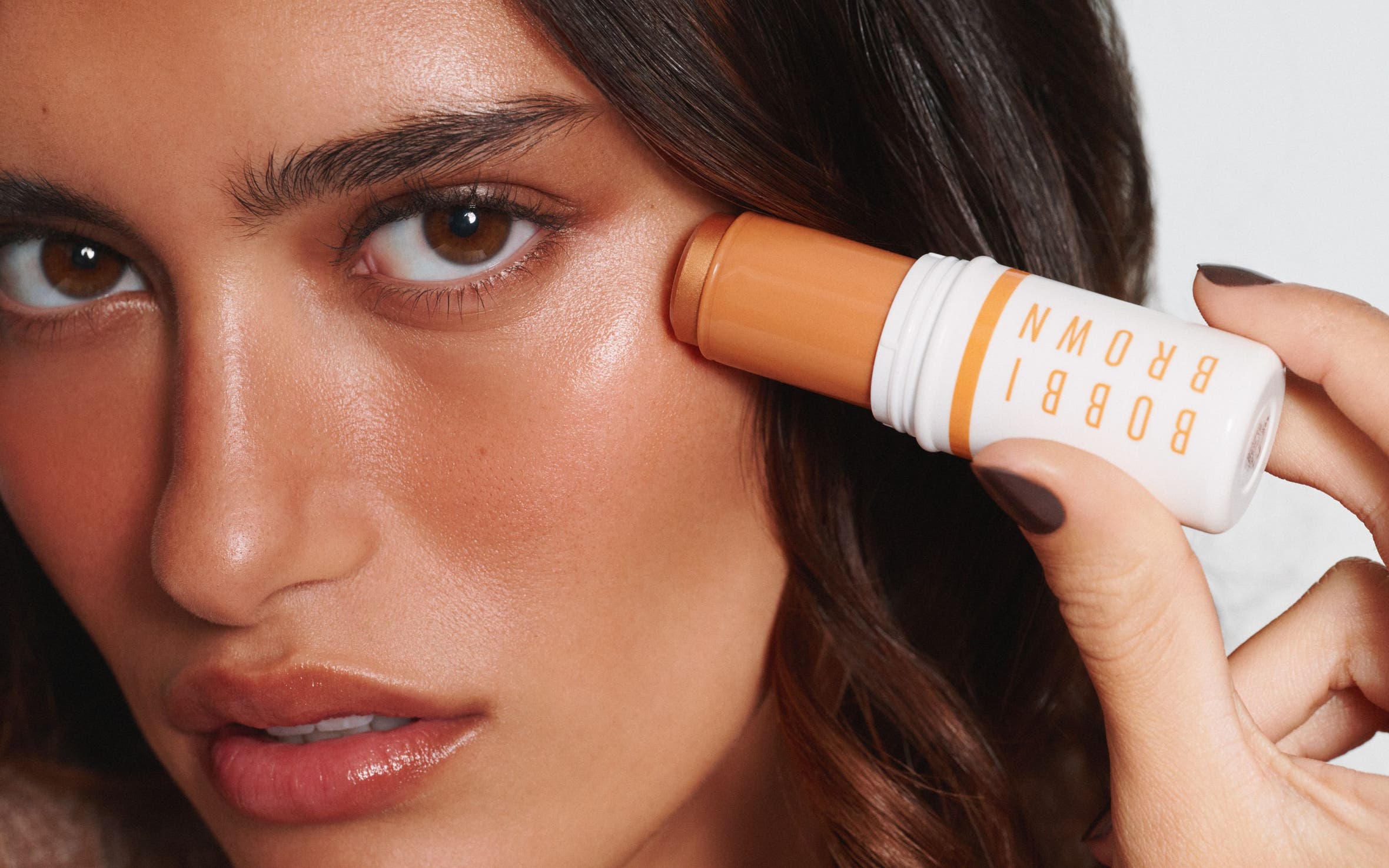 A woman applying a golden highlighter.