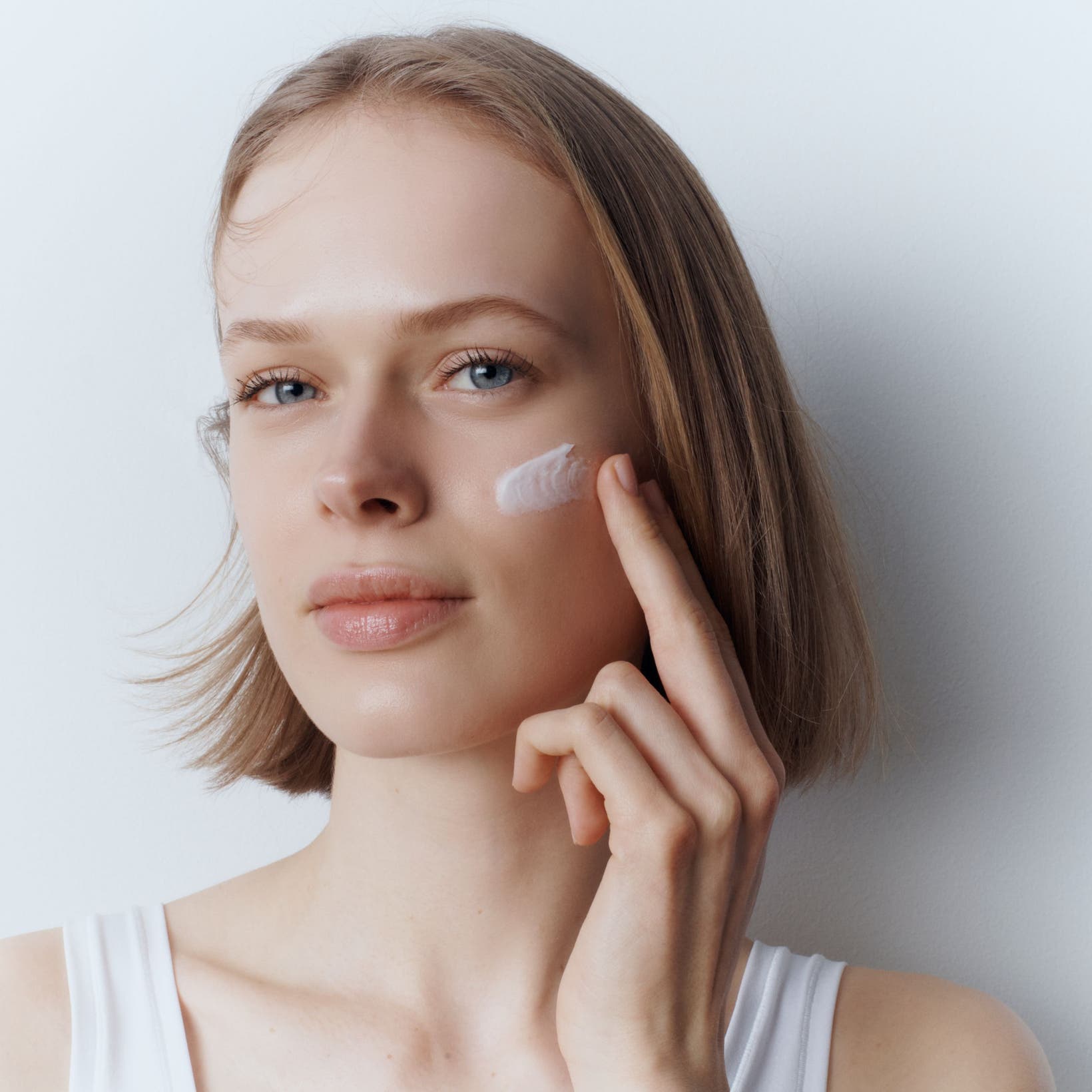 A woman applying face cream.
