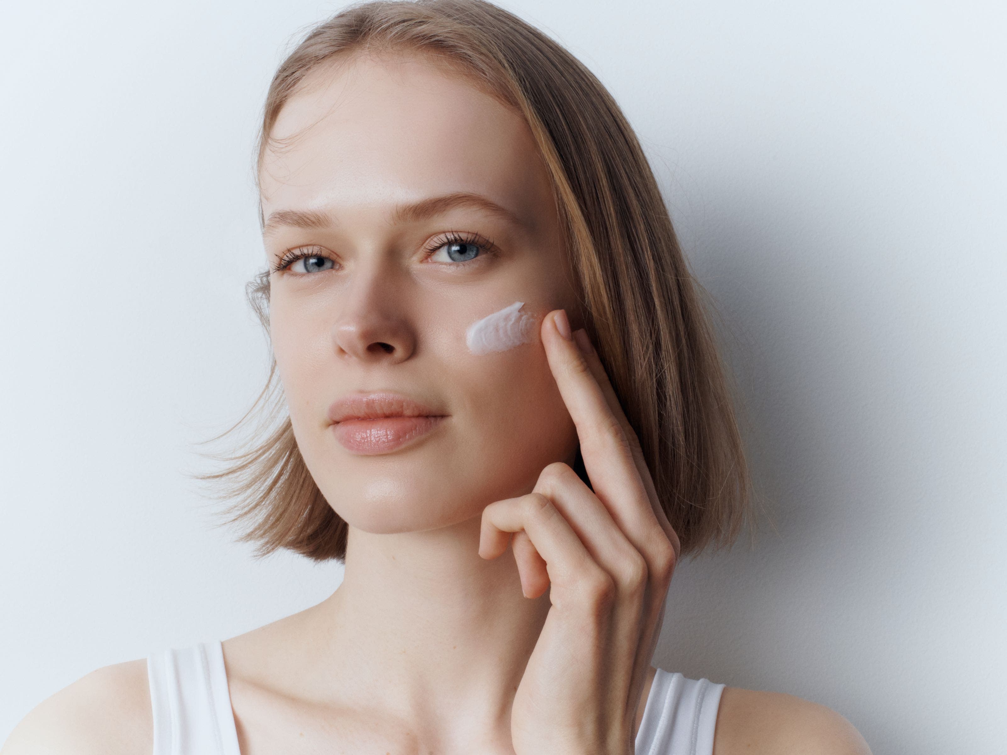 A woman applying face cream.