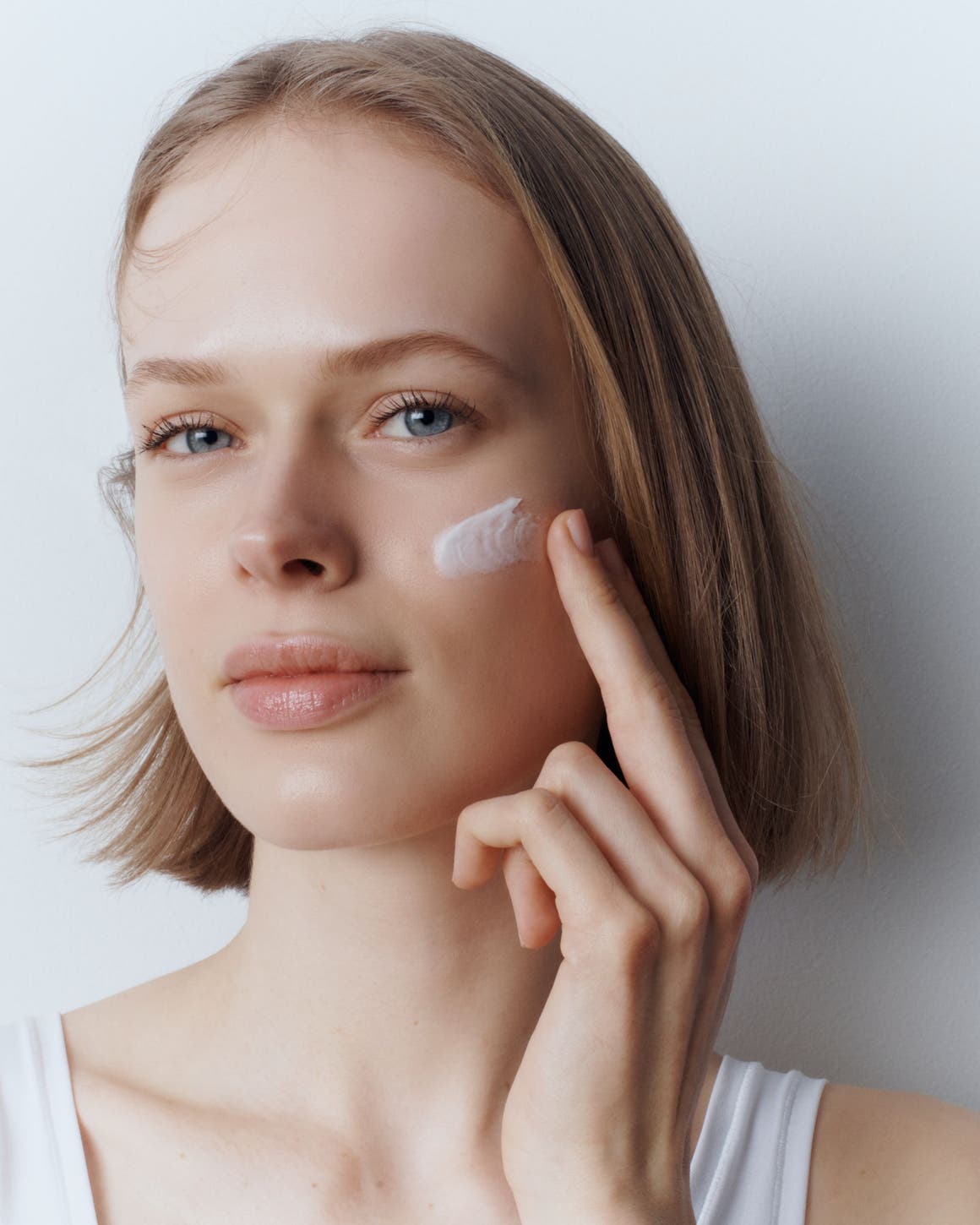 A woman applying face cream.