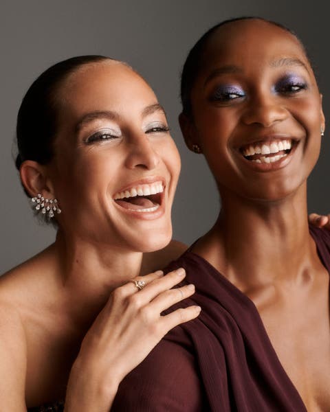 Two laughing women wearing sparkling eyeshadow.