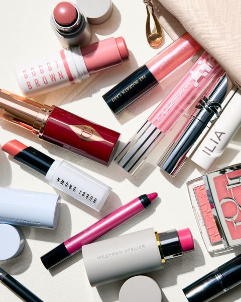 Beauty products spilling from a makeup bag including blush, mascara, eyeshadow, lipstick and eyeliner.