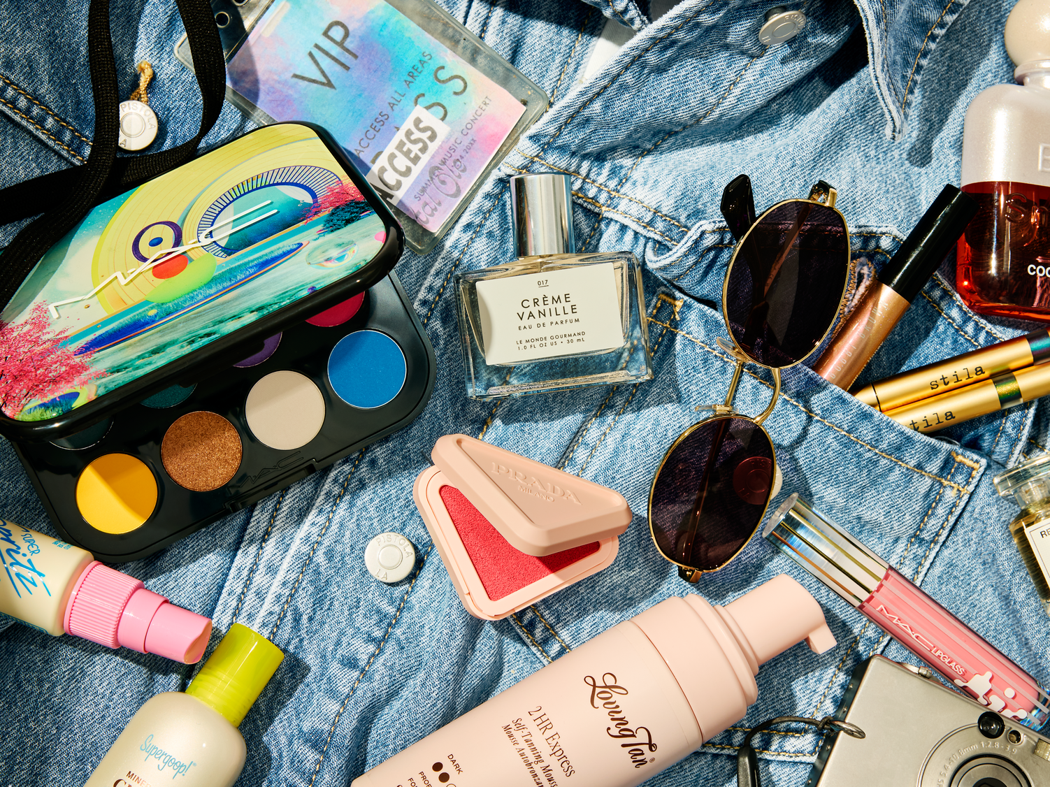 Beauty products and accessories laid out on top of a denim jacket.
