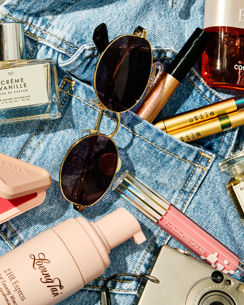Beauty products and accessories laid out on top of a denim jacket.