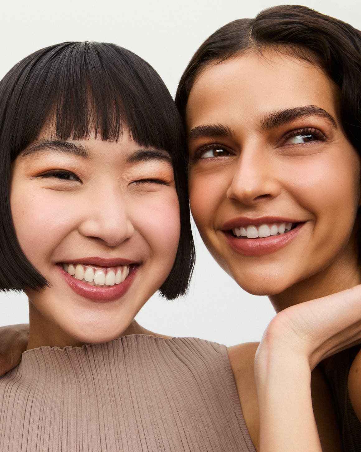 Three smiling women wearing makeup.