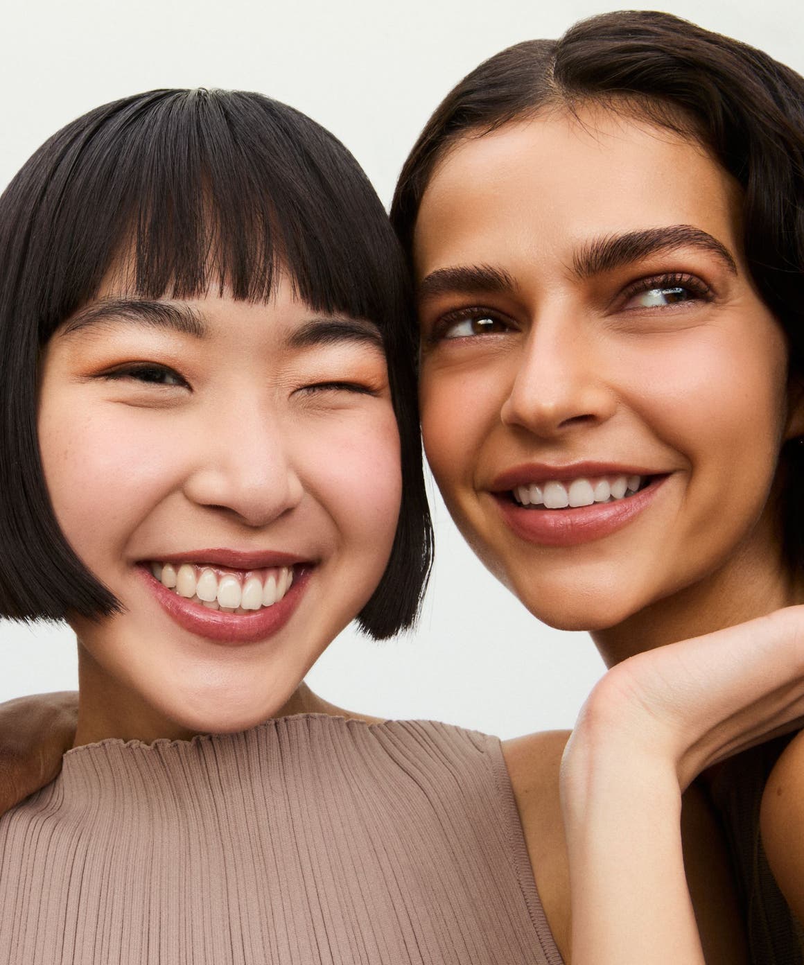 Three smiling women wearing makeup.