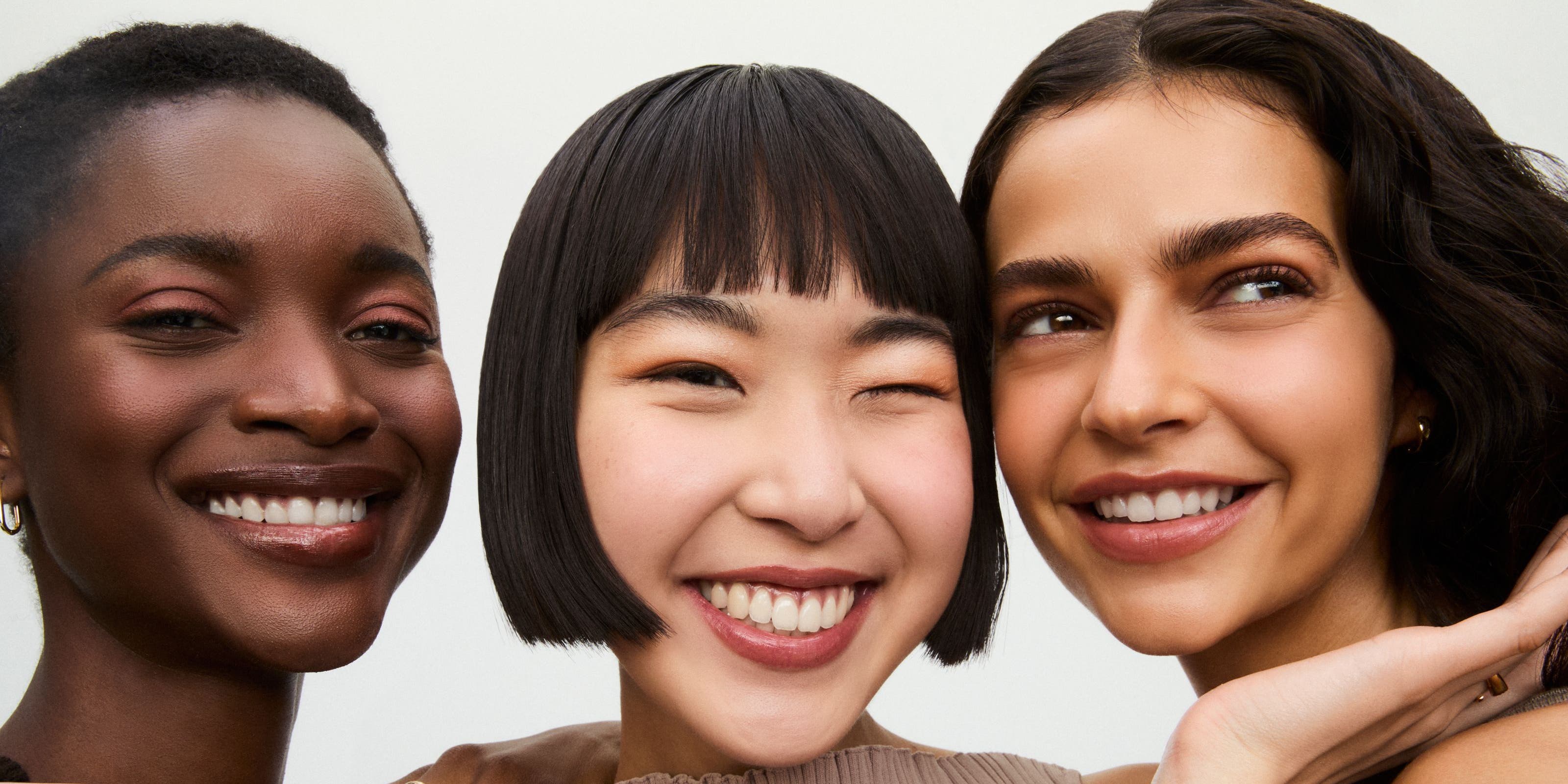 Three smiling women wearing makeup.