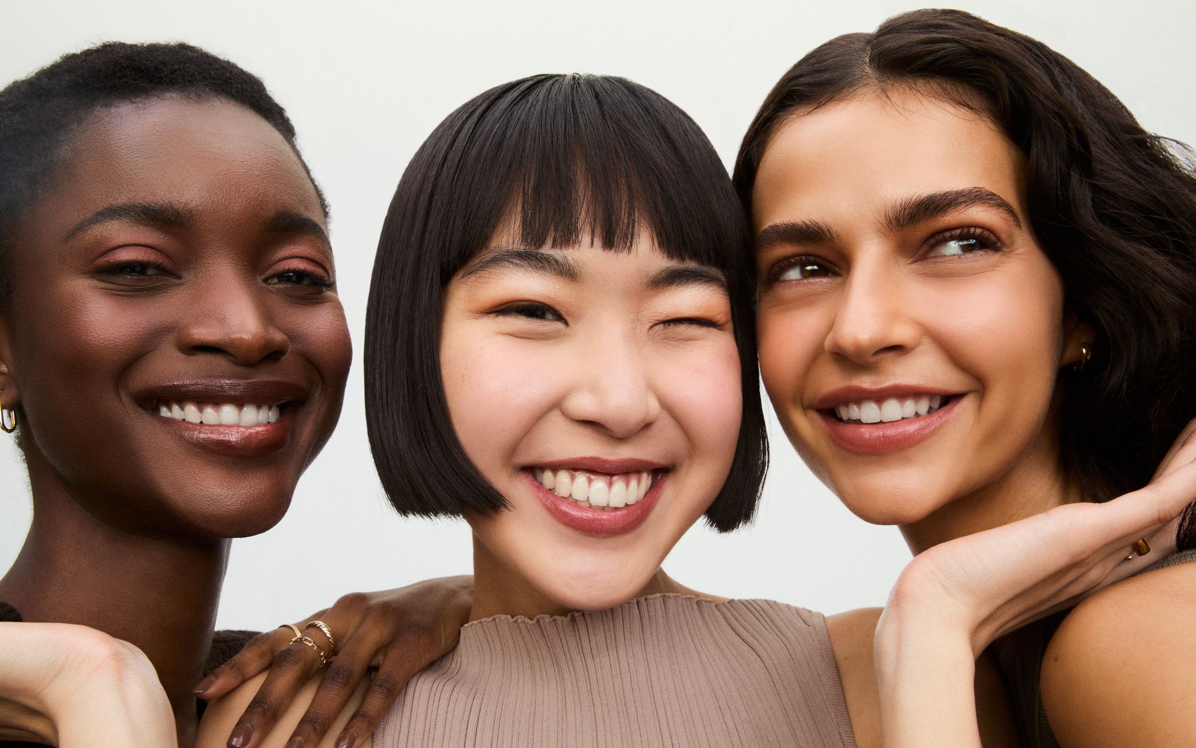 Three smiling women wearing makeup.