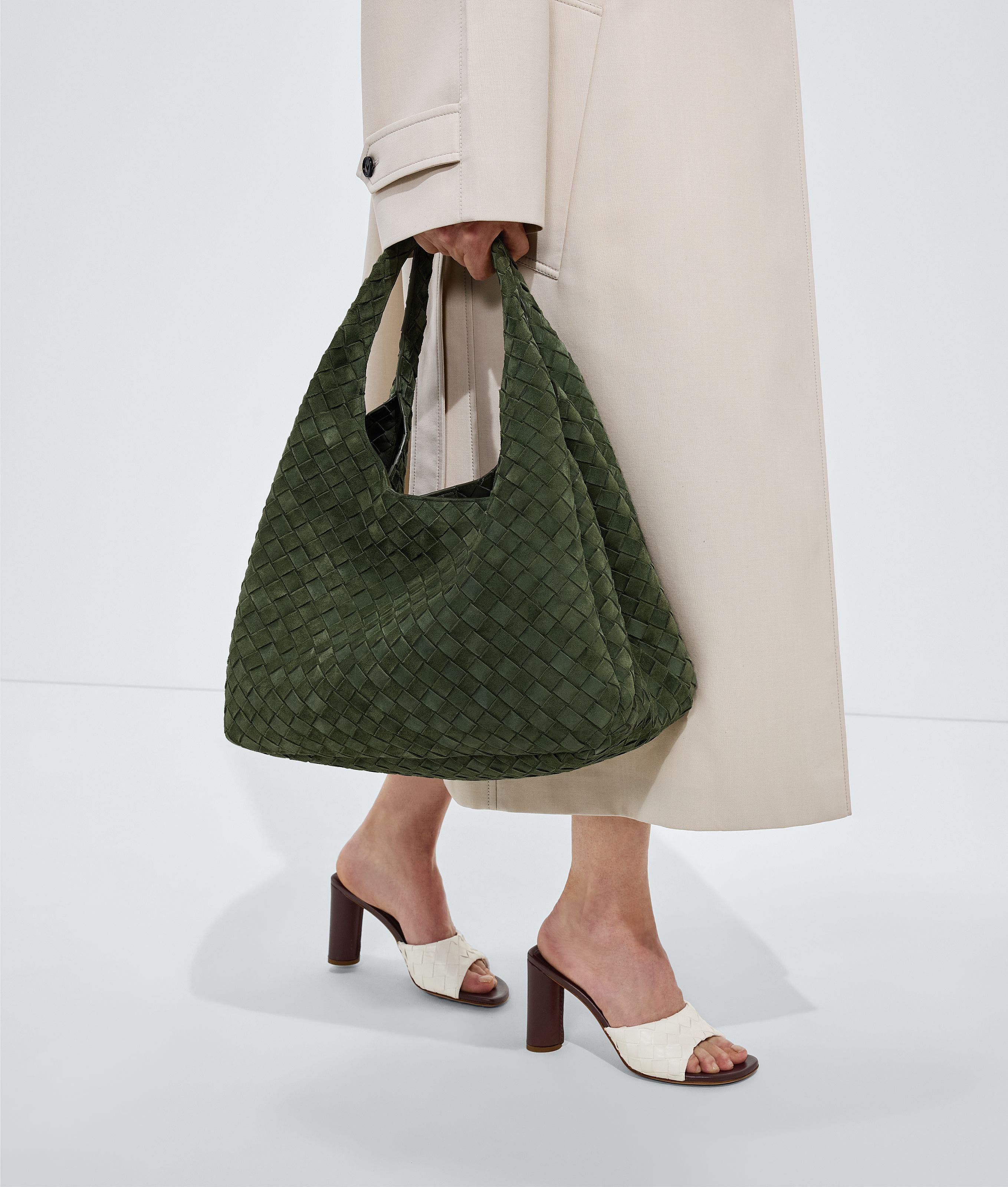A woman carrying a woven olive shoulder bag.