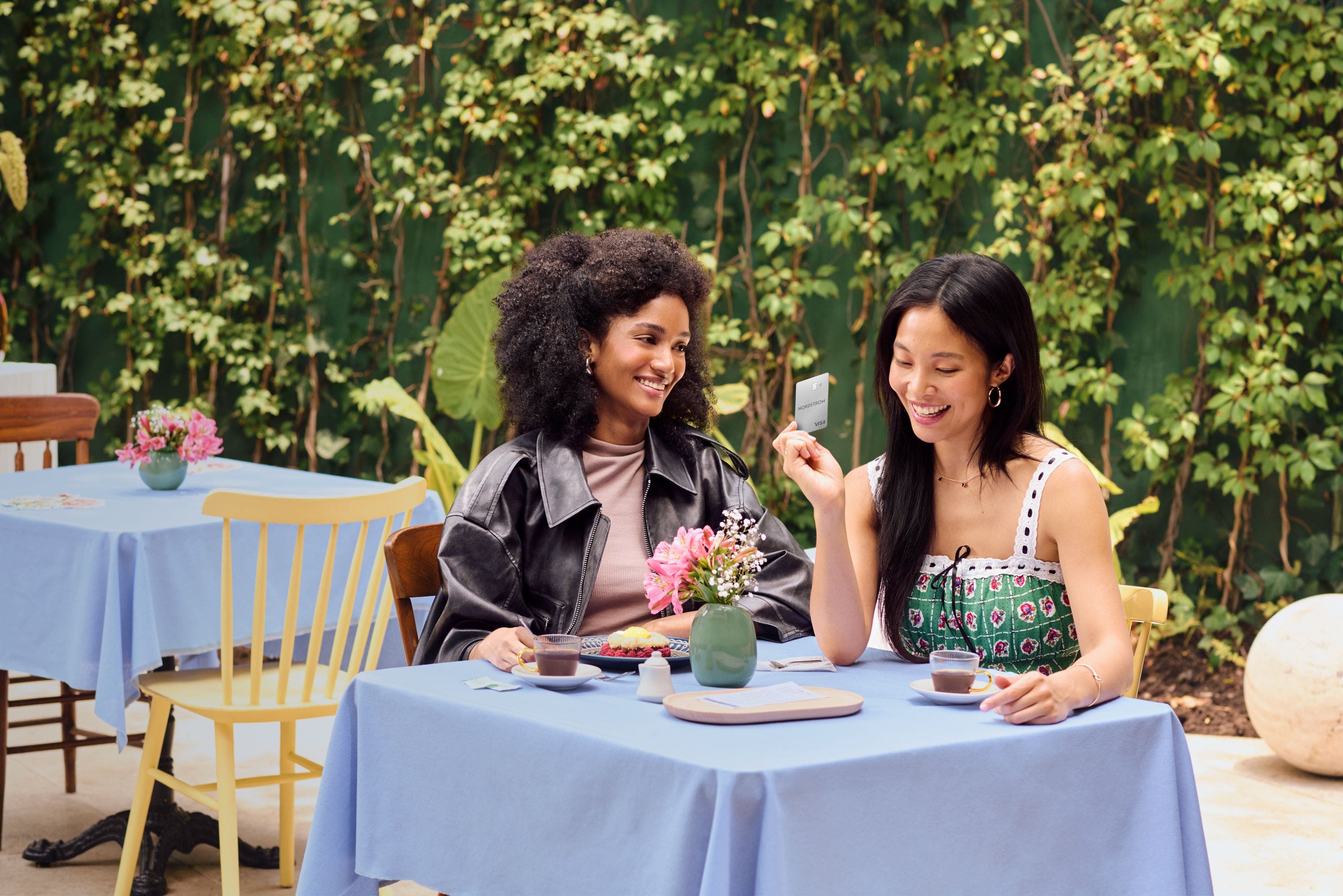 Smiling women paying at a restaurant with Nordstrom Visa card.