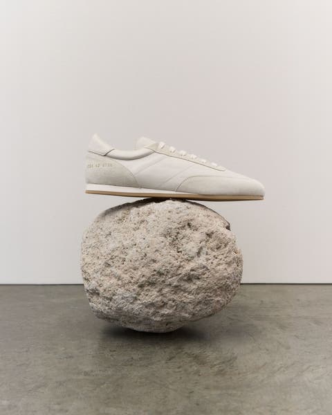 White running shoes balanced on a white rock.