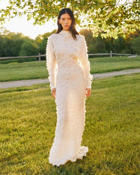 Women wearing a floor length white lace gown.