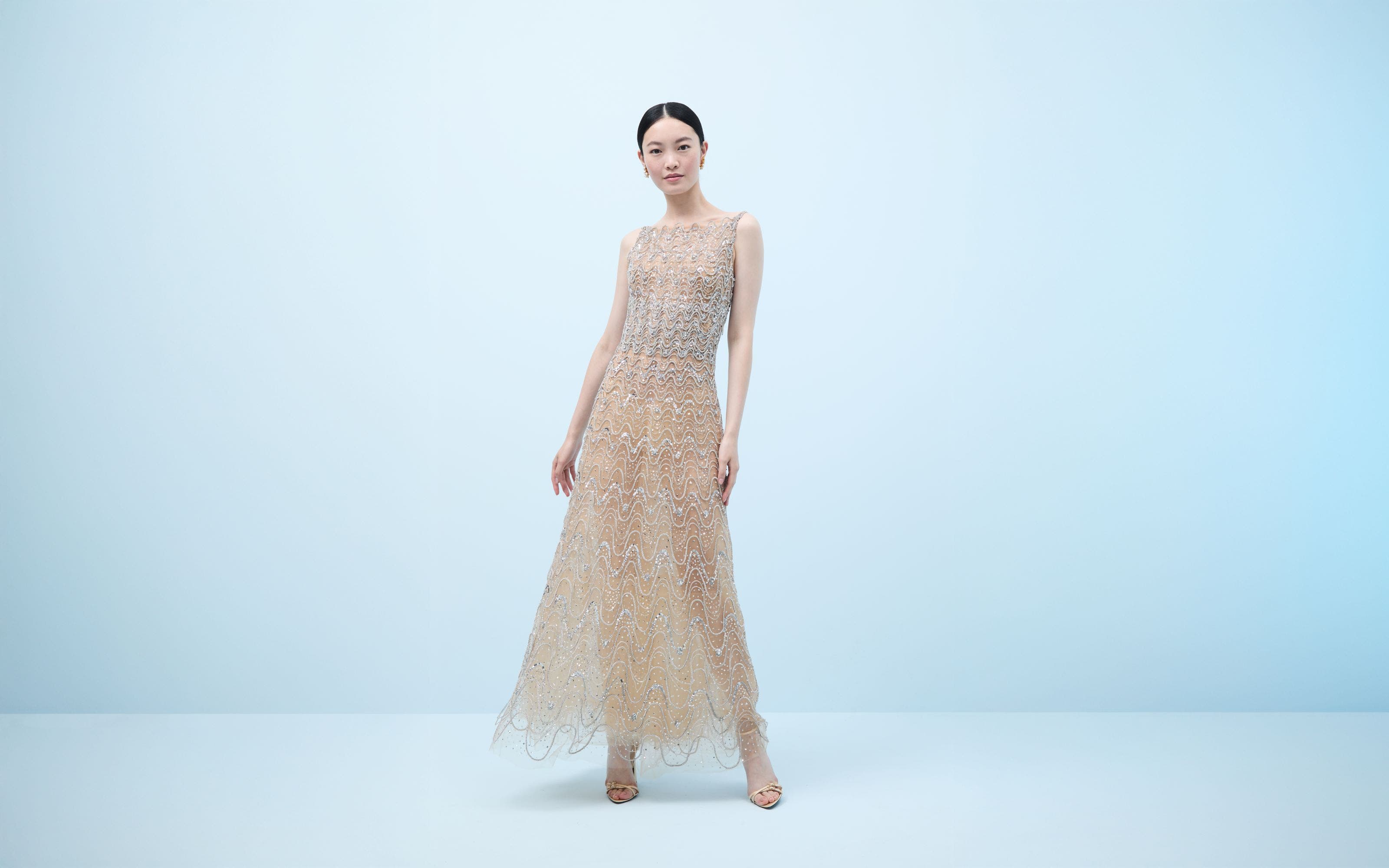 Woman wearing a crystal-embroidered evening gown and heels.